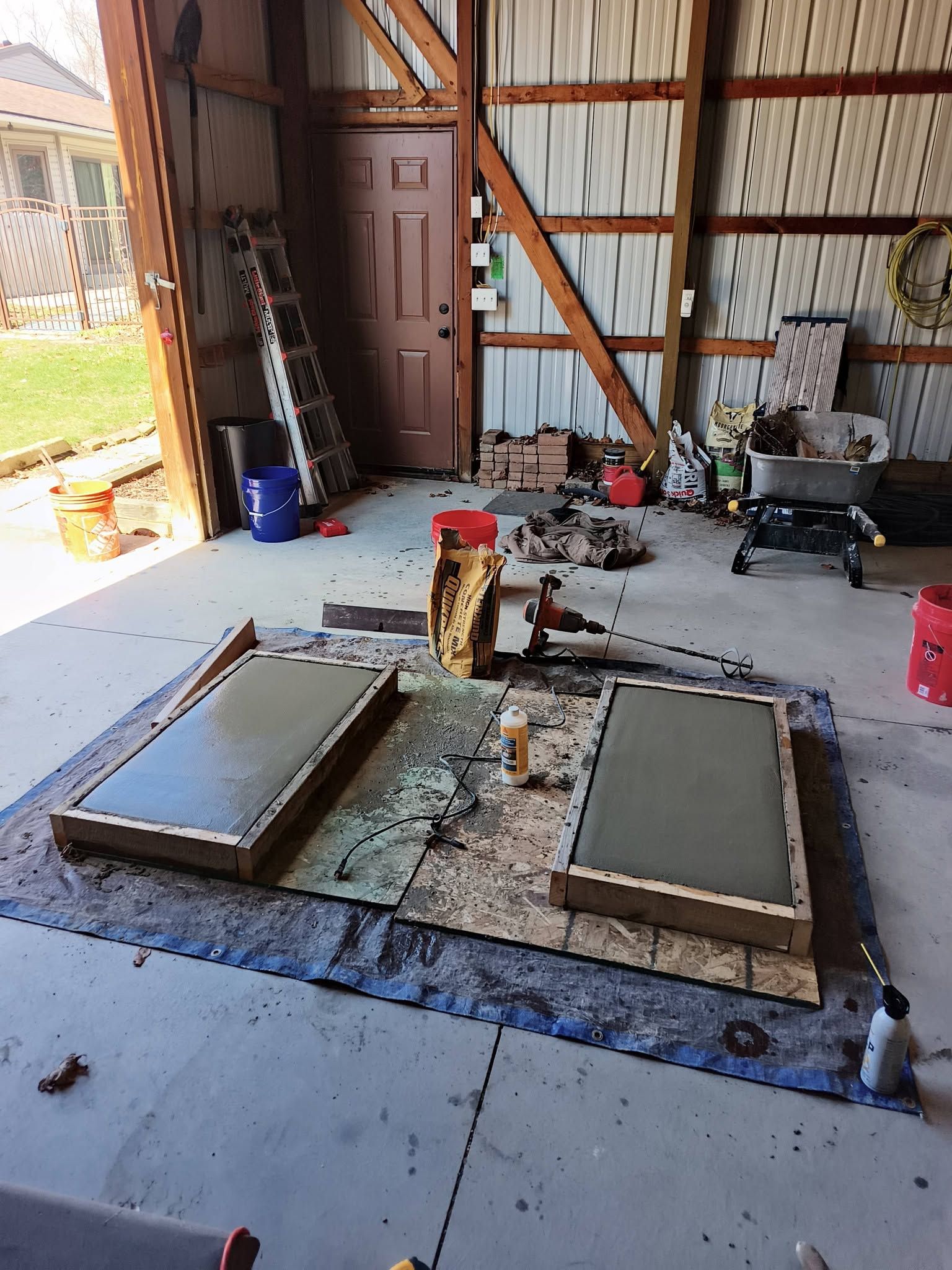 Workshop floor with two wet concrete forms and tools in a metal barn interior