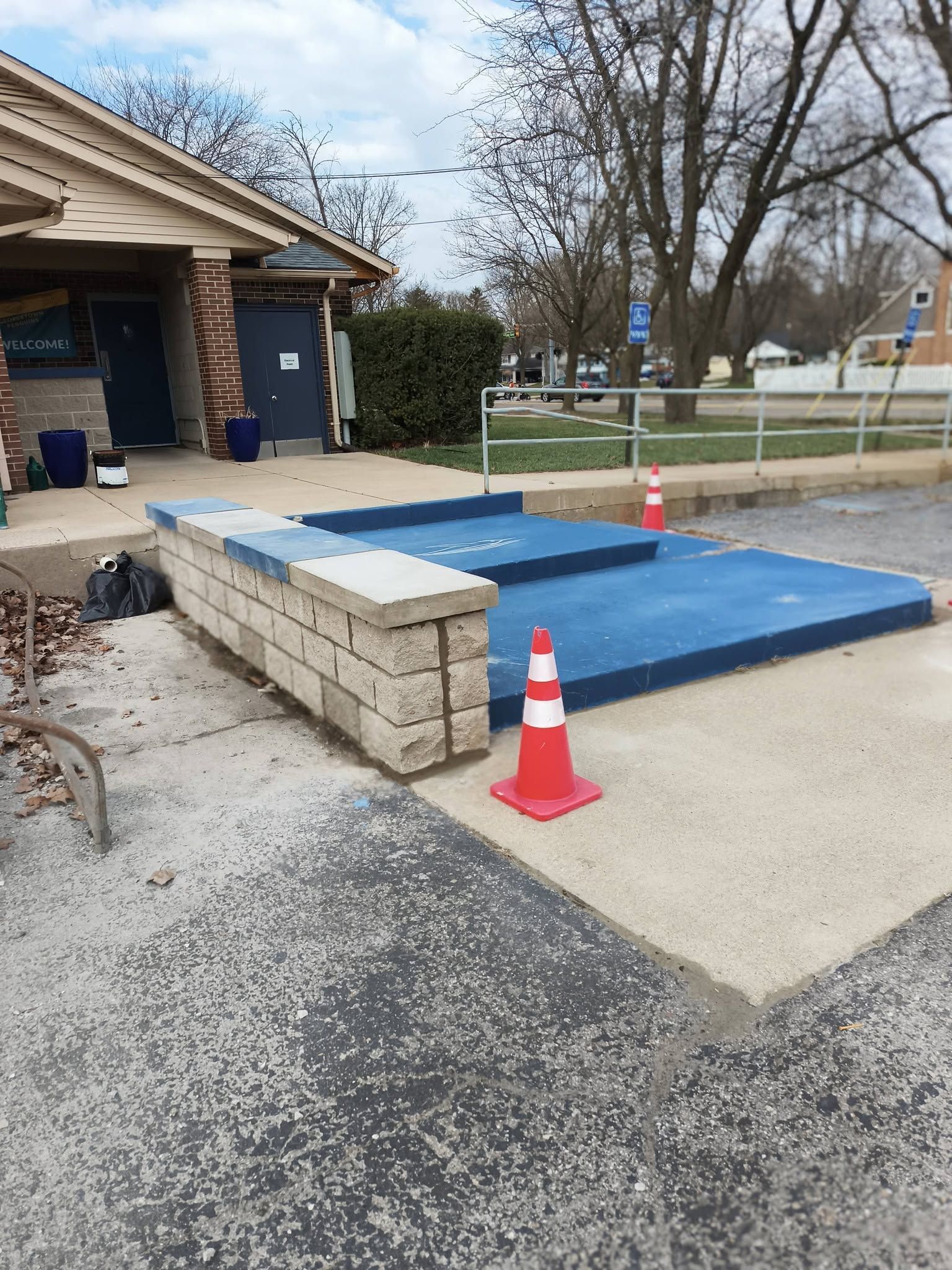 Blue temporary platform and orange cones on a driveway beside a house outdoors