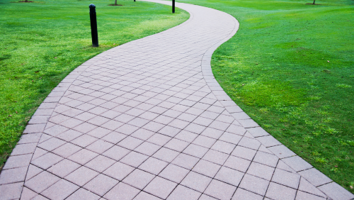 Curved white stone walkway through a green park lawn