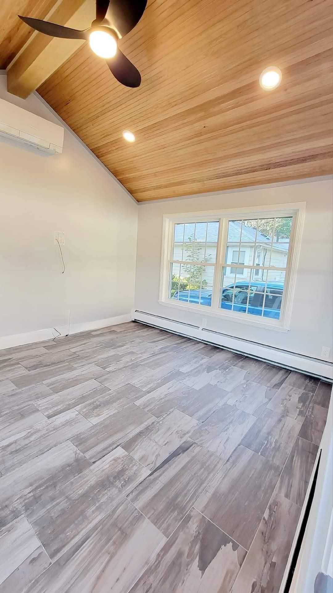 Empty renovated family room in Melrose Massachusetts showing new wood ceiling recessed lighting and gray tile floor