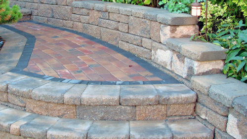 Curved brick patio steps with stacked stone retaining walls and greenery beside them