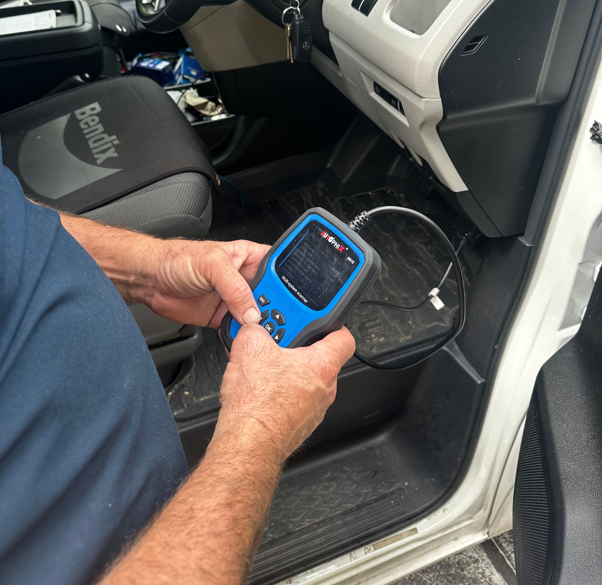 Person using a handheld diagnostic device inside a car near the driver’s seat and dashboard — Calvin's Mobile Mechanics In Palm Beach, QLD