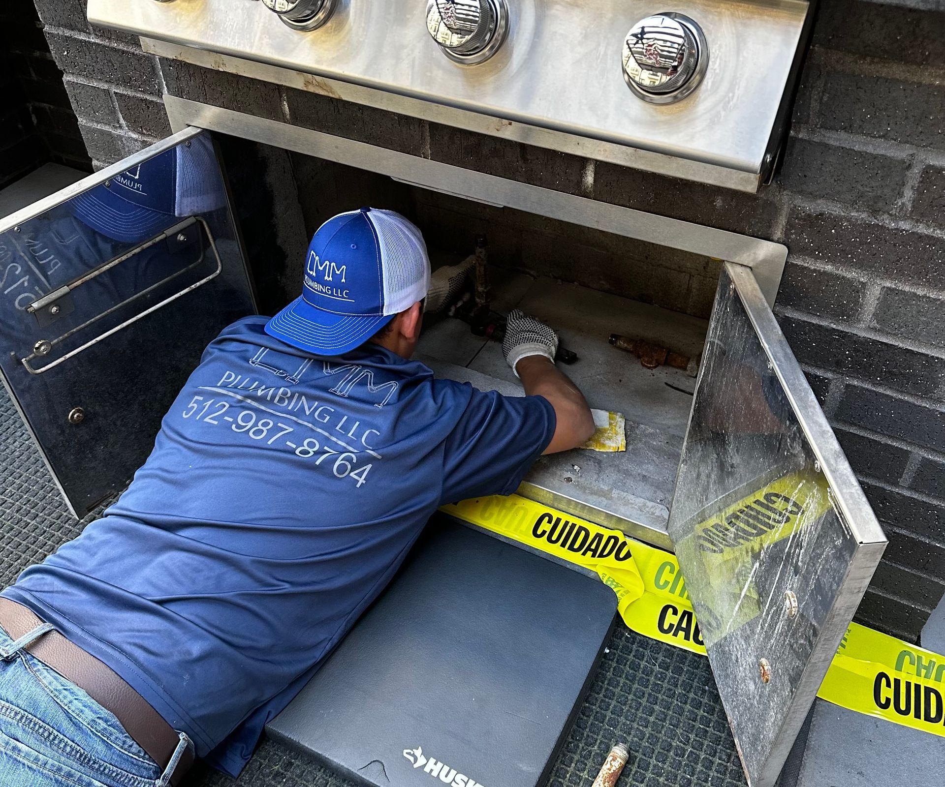 a man in a blue shirt is working on a grill
