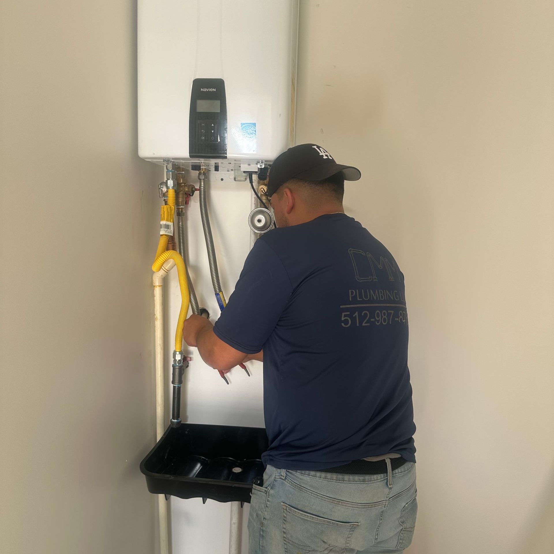 a man in a blue shirt is working on a water heater .