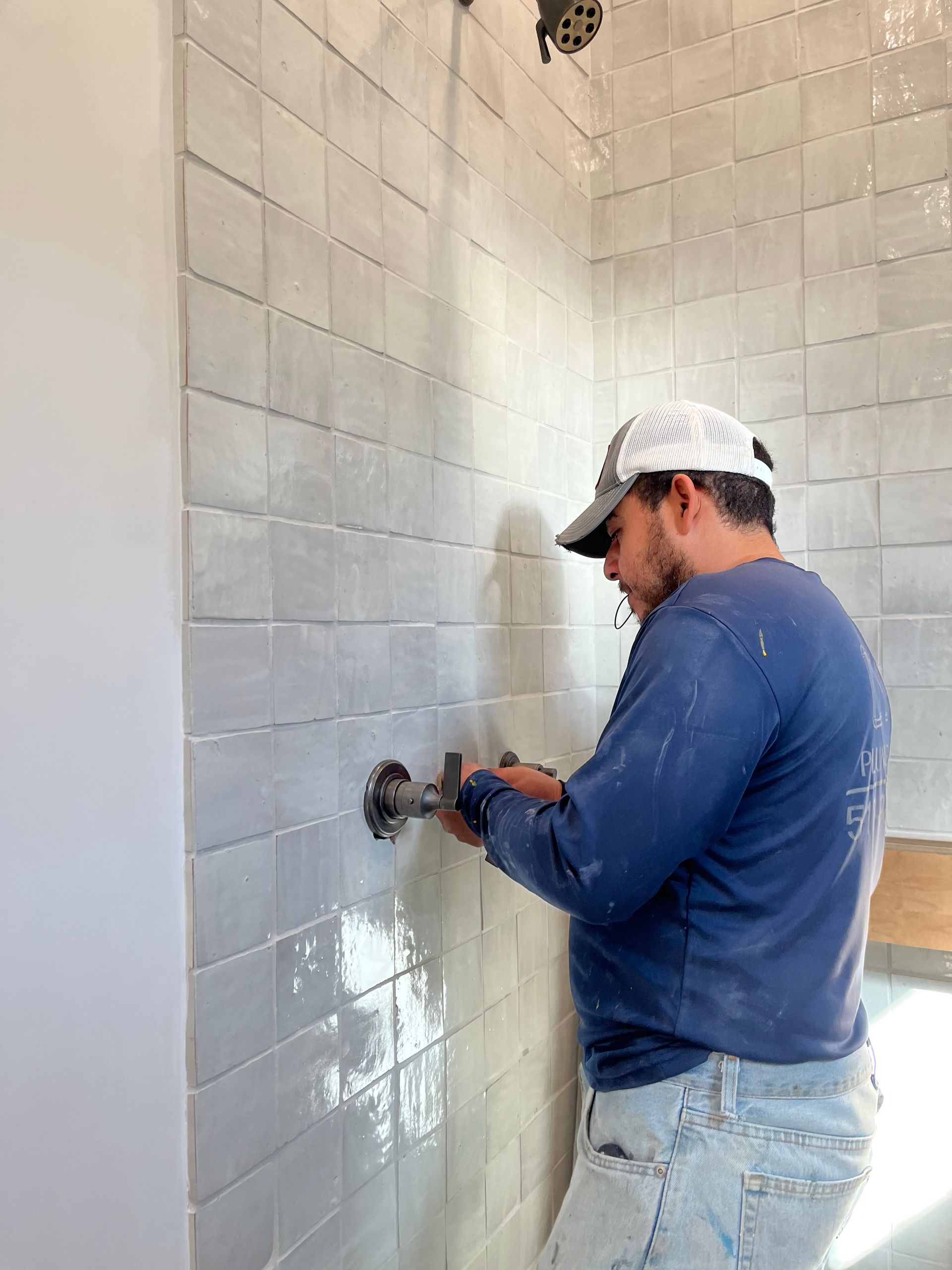 a man is working on a shower head in a bathroom .