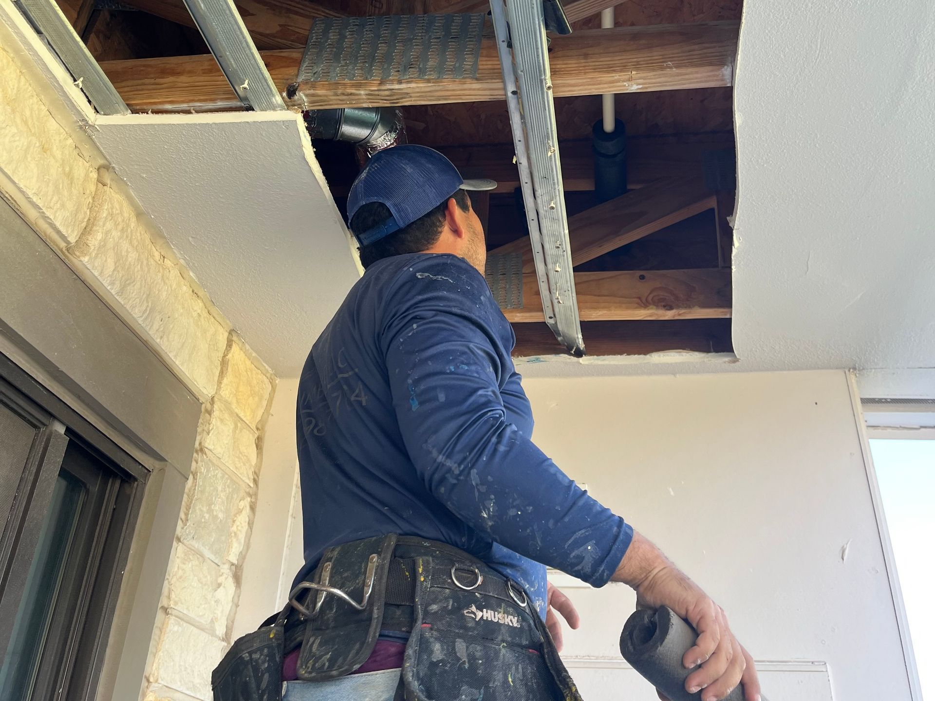 a man is working on the ceiling of a building .