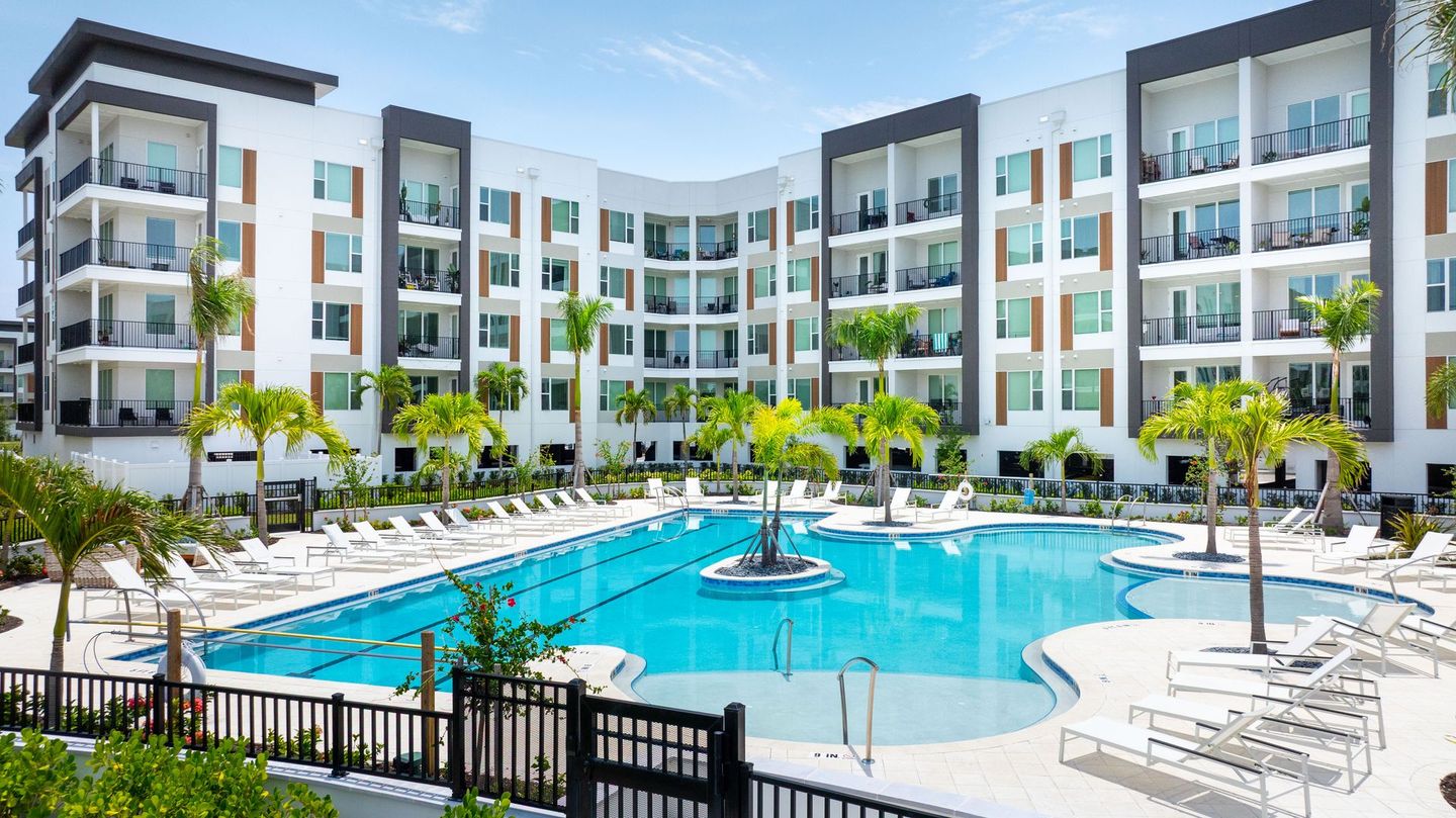 A large apartment building with a large swimming pool in front of it.