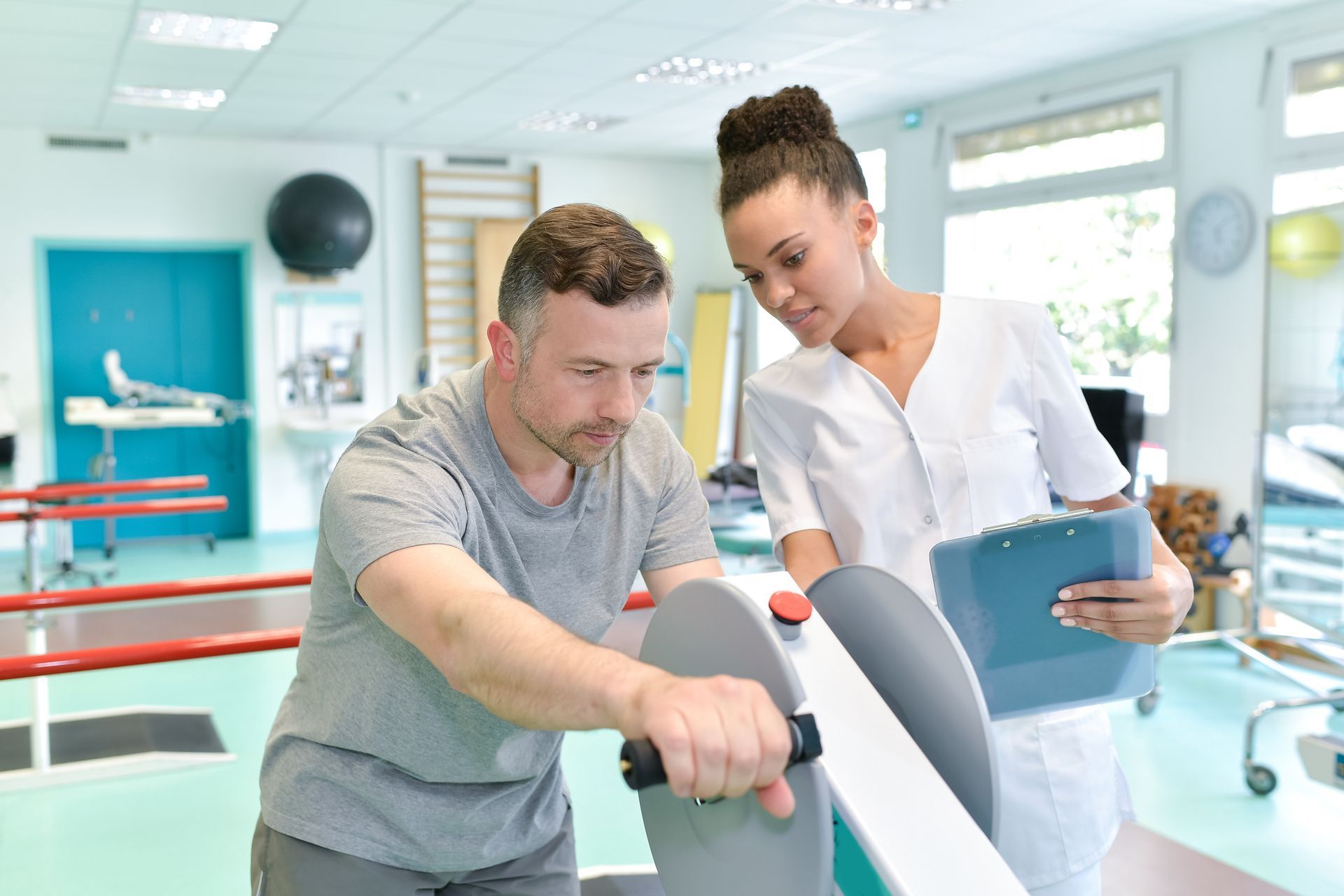 A physical therapy session in a rehabilitation center, showing a male patient using an exercise machine. A physical therapy session in a rehabilitation center, showing a male patient using an exercise machine.