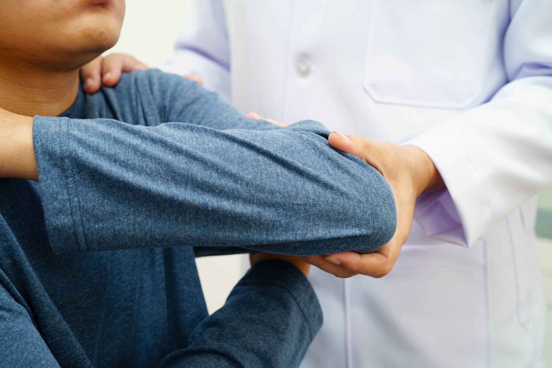 Doctor representing chronic pain management physician performing shoulder therapy for mobility.