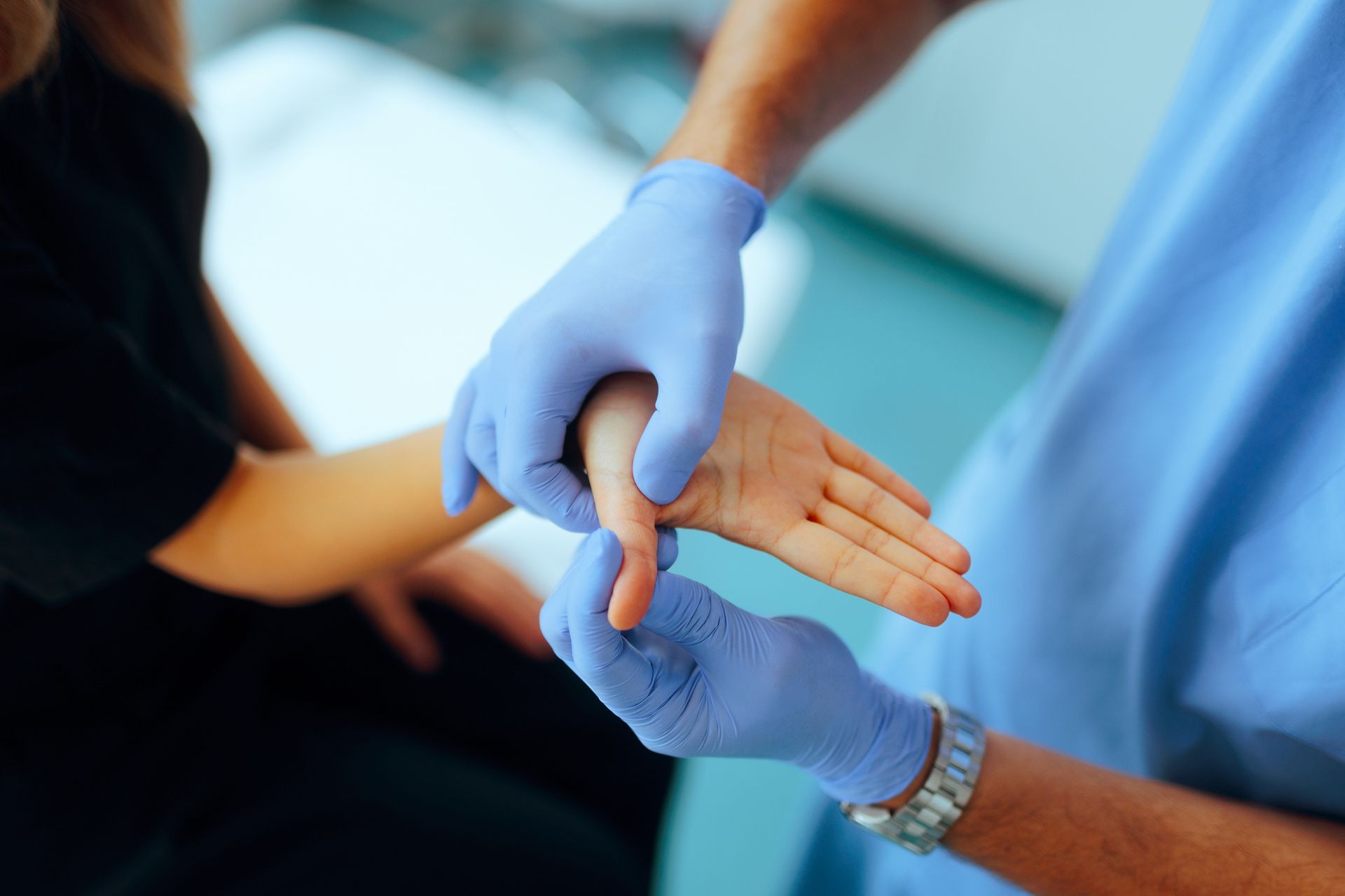 A woman with inflammatory disease getting help with hand pain and numbness treatment. A medical professional in blue gloves examines a patient's hand in a clinical setting.