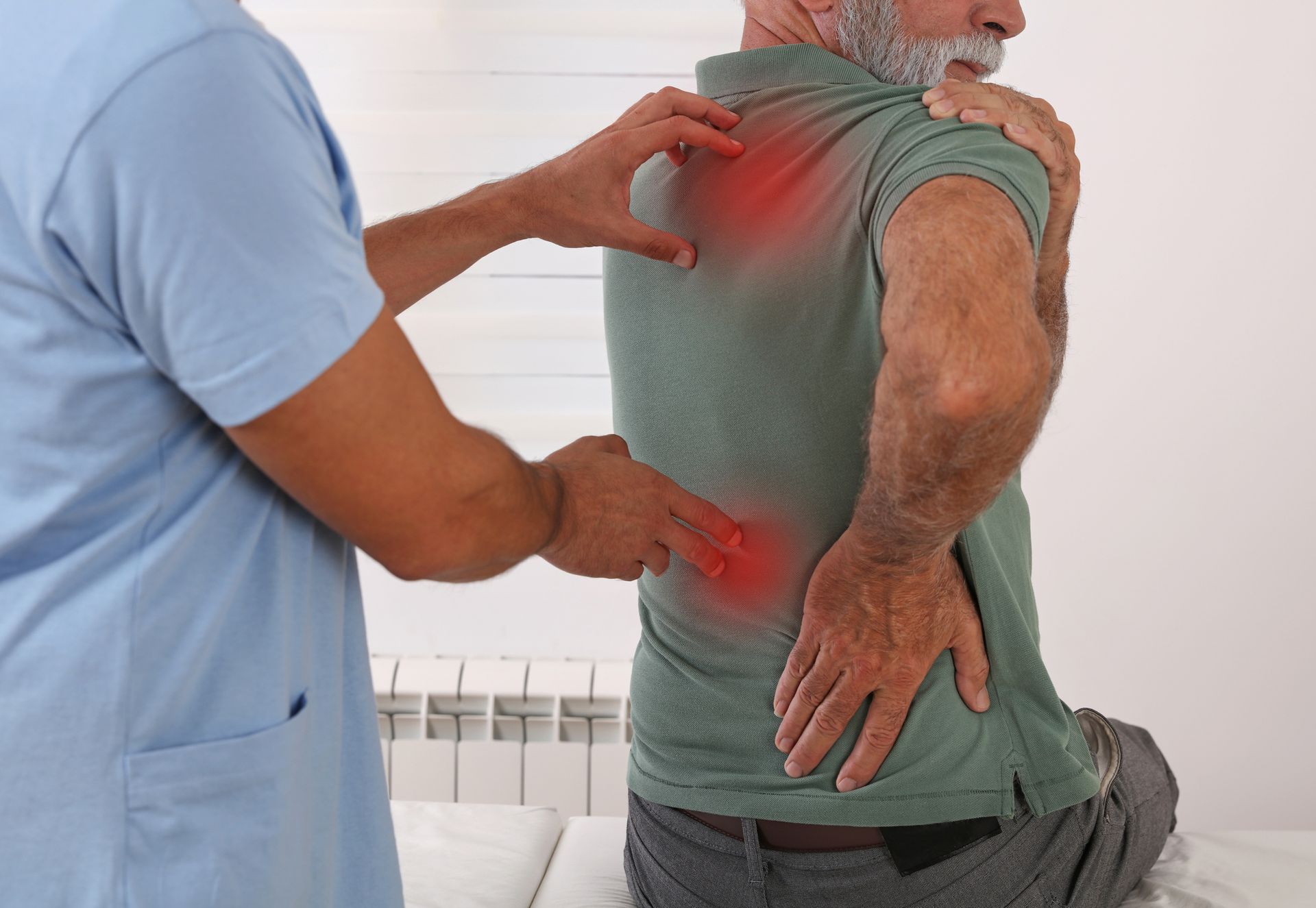 Healthcare provider examining a person's back; red areas highlight pain.