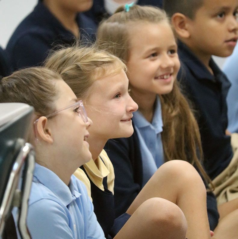 Four children smiling, sitting close together. Admissions | Immanuel Lutheran School | Belvidere, IL