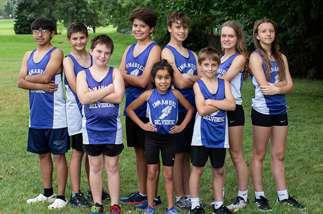 Cross country team in blue and white uniforms, arms crossed, on grass. Immanuel Lutheran School | Belvidere, IL