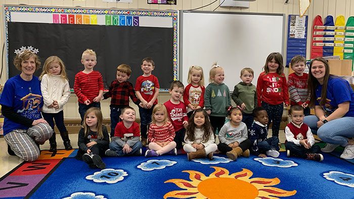 Two adults with a group of children, possibly a class, in a classroom. Pre-K & Kindergarten | Immanuel Lutheran School | Belvidere, IL