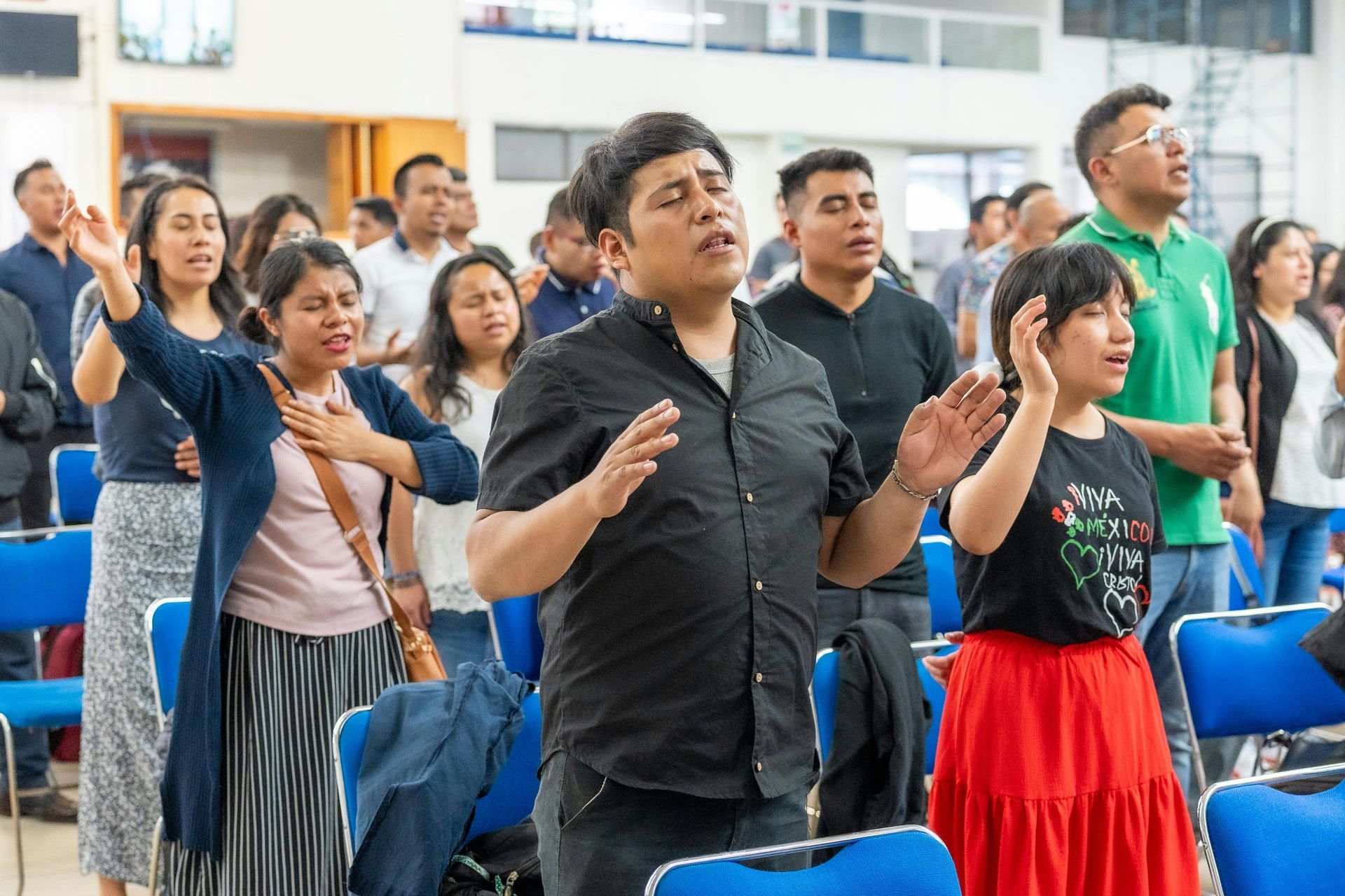 Group of people in a church singing with arms raised. Discipleship | Immanuel Lutheran School | Belvidere, IL