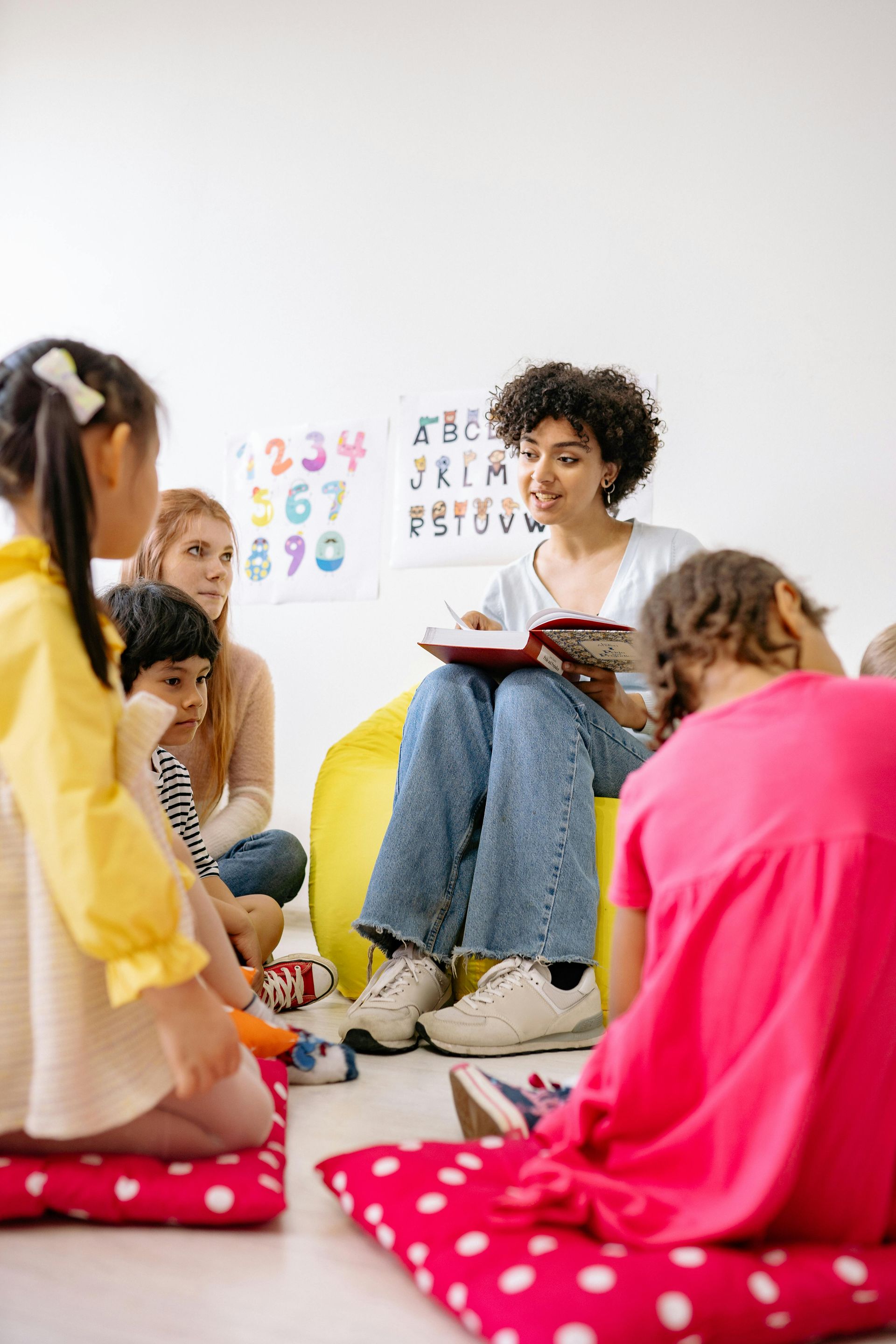 Teacher reads to children seated on cushions in a brightly lit room. The Immanuel Difference | Immanuel Lutheran School | Belvidere, IL