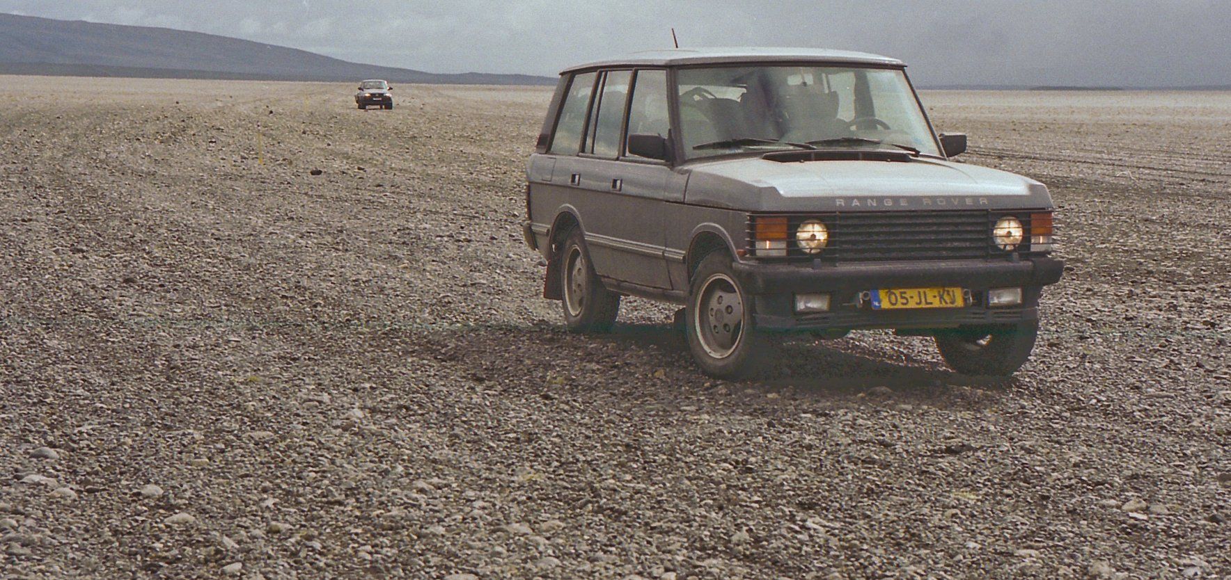 Een range rover staat midden in een woestijn geparkeerd