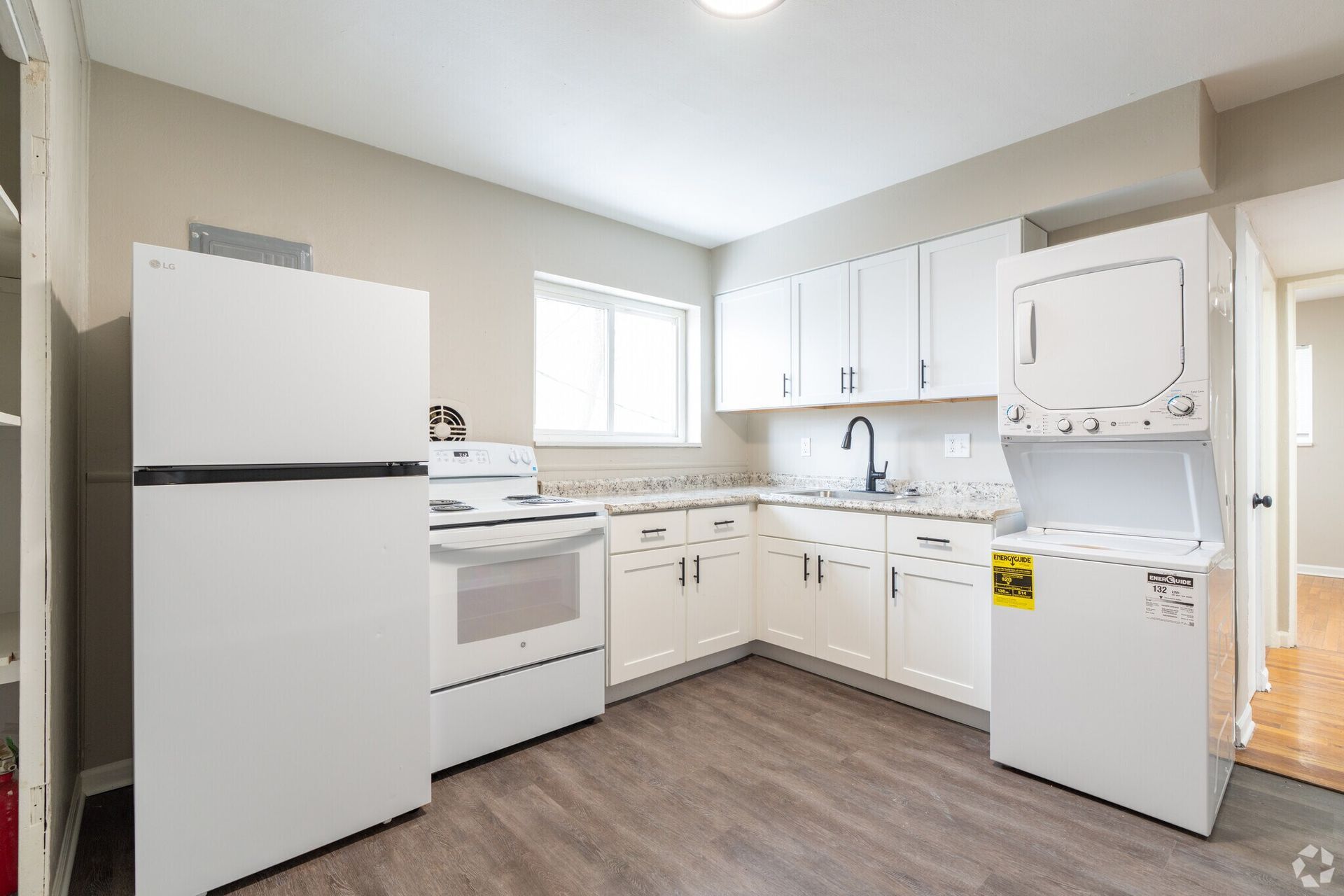 Bright white kitchen with fridge, stove, cabinets, and dishwasher on wood-look floor