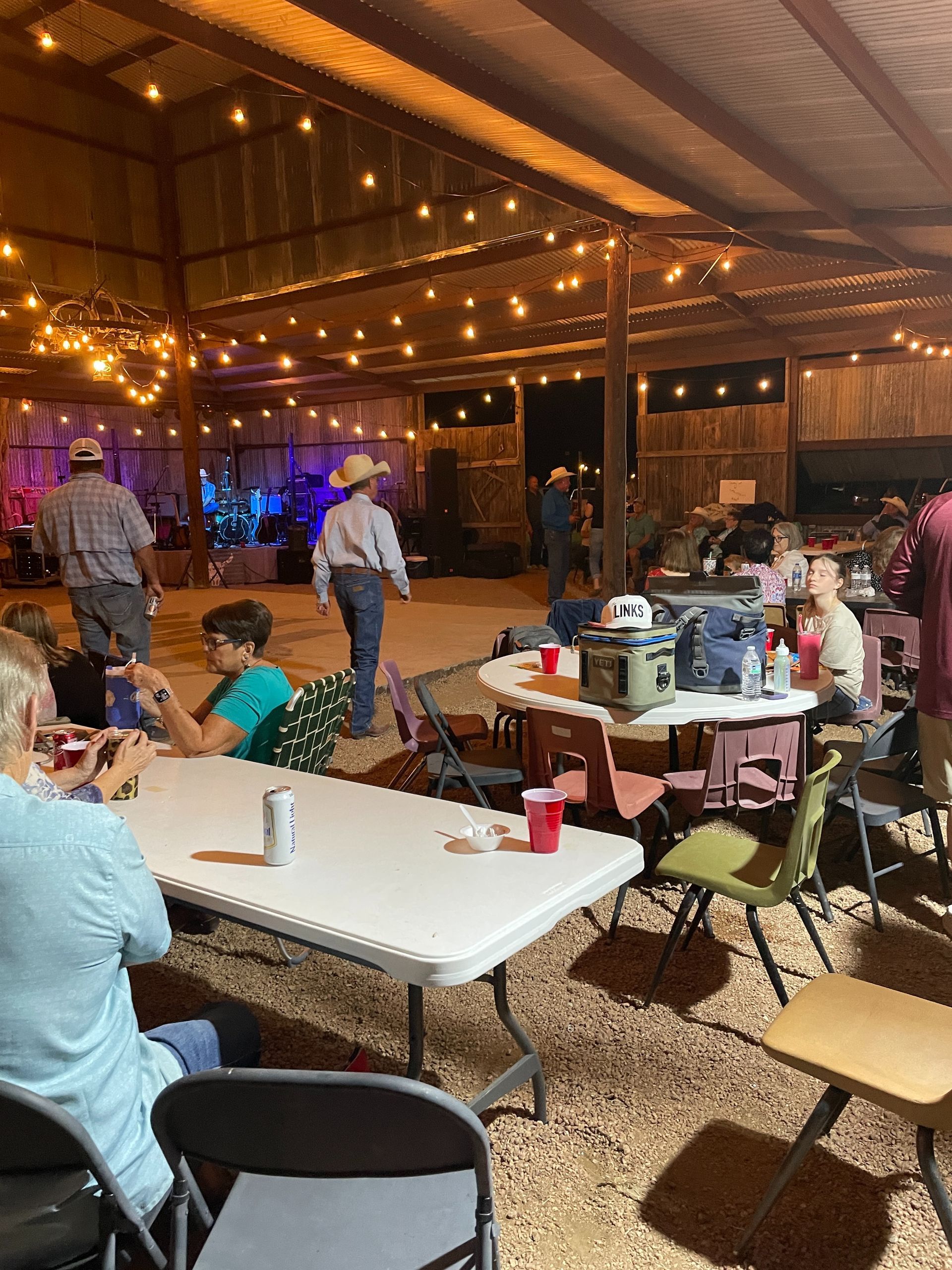 Outdoor patio restaurant with string lights, tables, and people dining under a covered roof