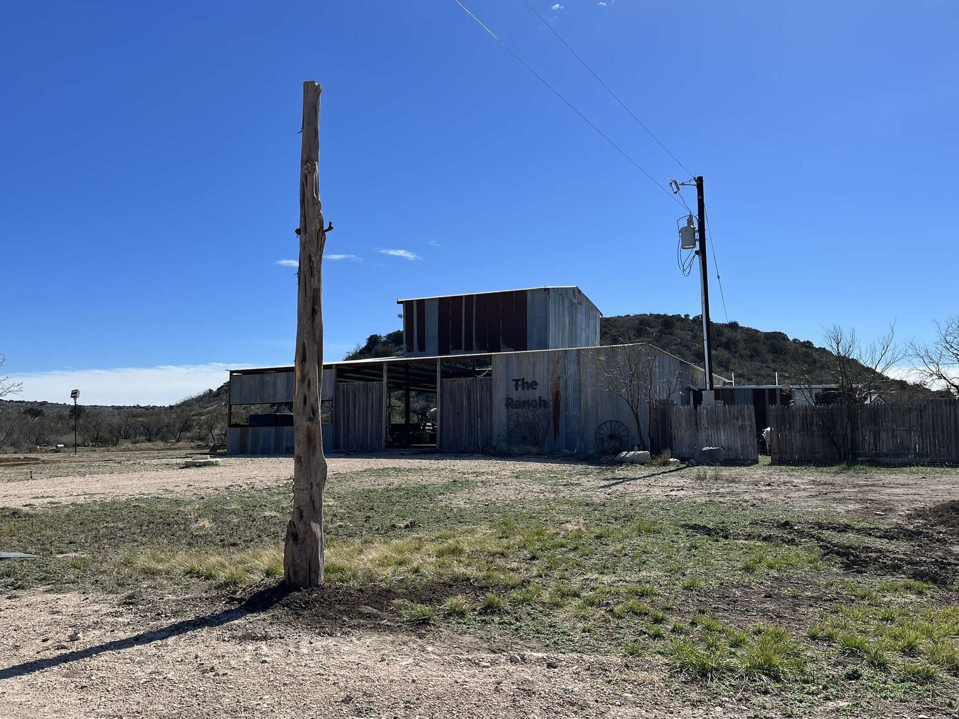 Abandoned weathered building in a dry field under a clear blue sky.
