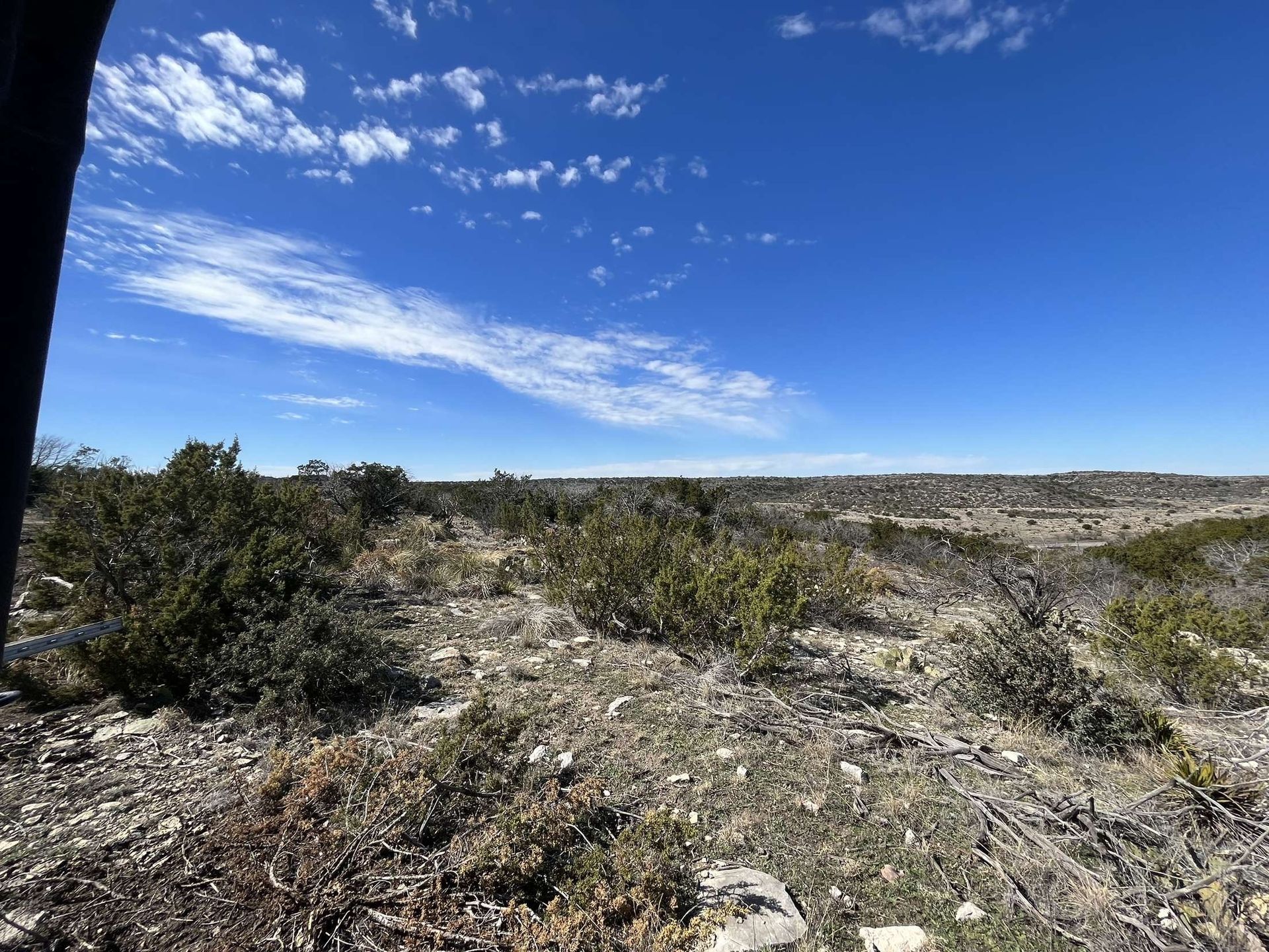 Rocky scrubland under a bright blue sky with scattered clouds