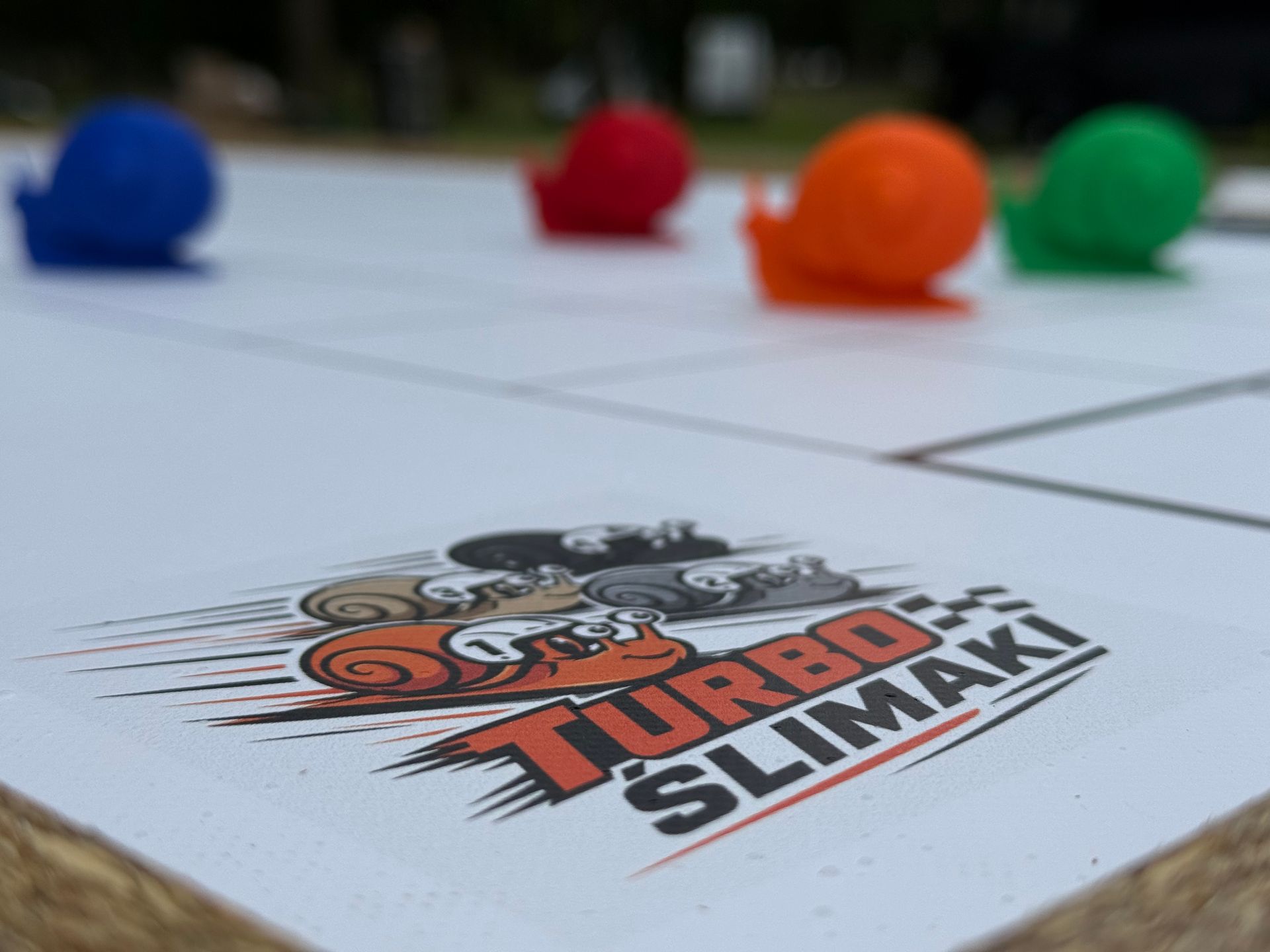 Kolorowe kulki ustawione na białej powierzchni z logo Turbo Slimak