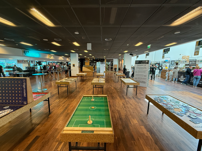 Kryty salon gier z stołami do gry w shuffleboard na drewnianej podłodze pod jasnymi światłami sufitowymi