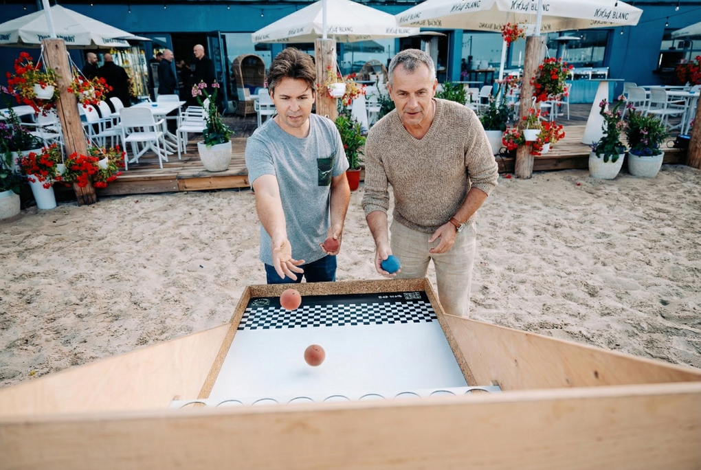 Dwie osoby grają w shuffleboarda na świeżym powietrzu w kawiarni przy plaży