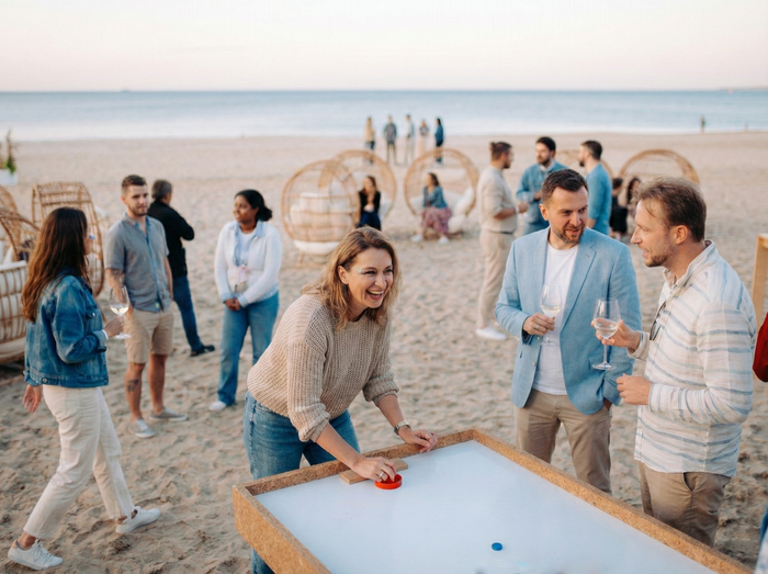 Ludzie grający w grę planszową na plaży, w tle inni rozmawiający