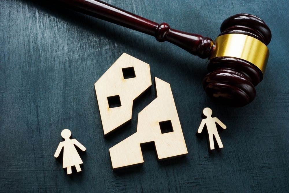 Court gavel beside torn paper family icons on a dark surface, symbolizing divorce or custody dispute