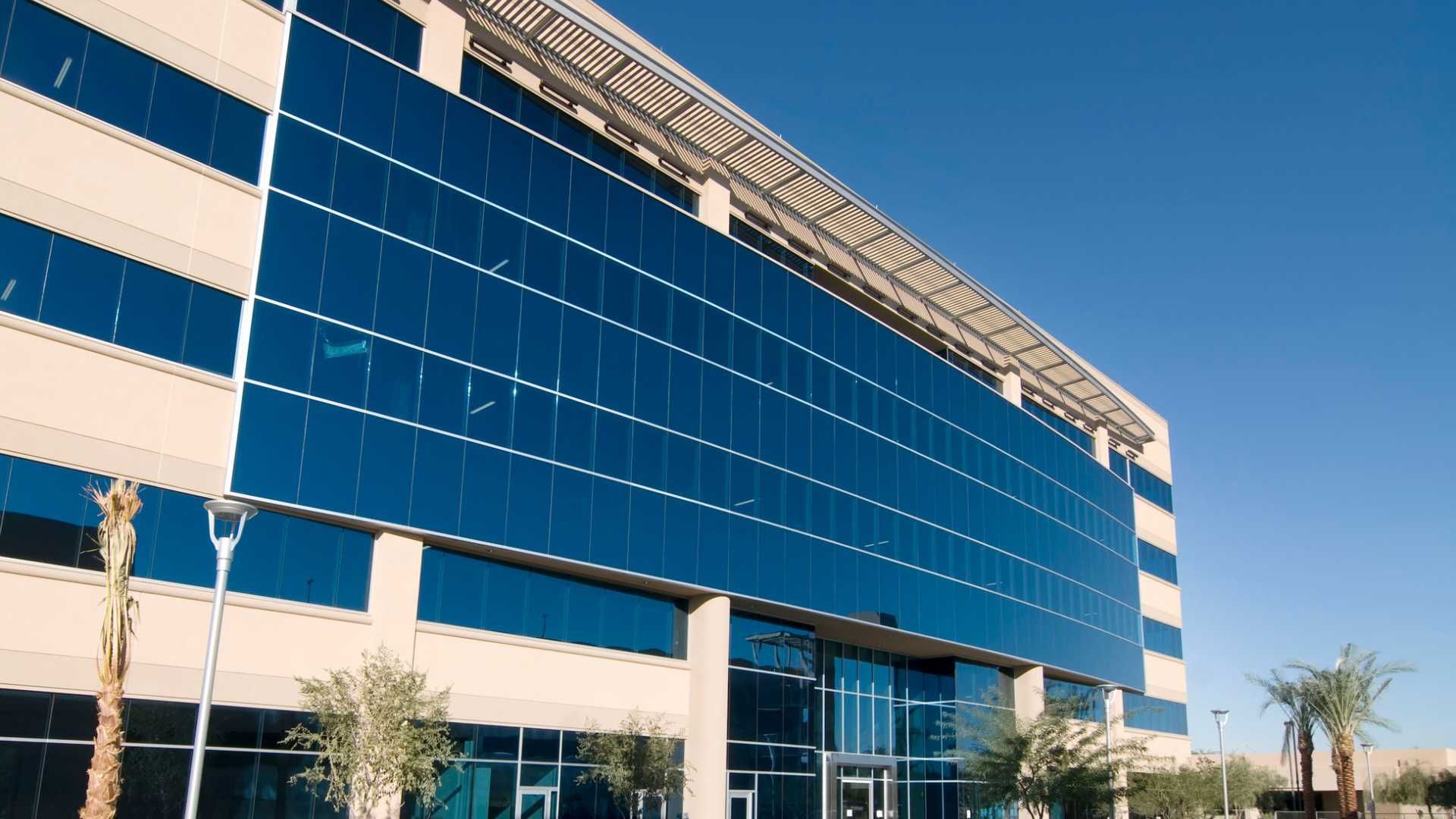 A large building with a lot of windows and palm trees in front of it