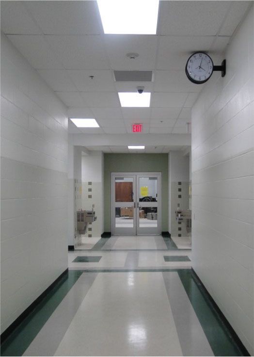 A hallway with a clock on the wall and a red exit sign