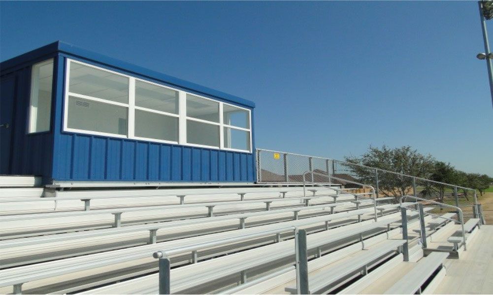 A stadium with bleachers and a blue building in the background