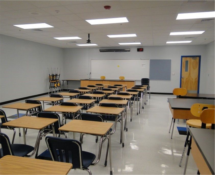 A classroom with wooden desks and blue chairs