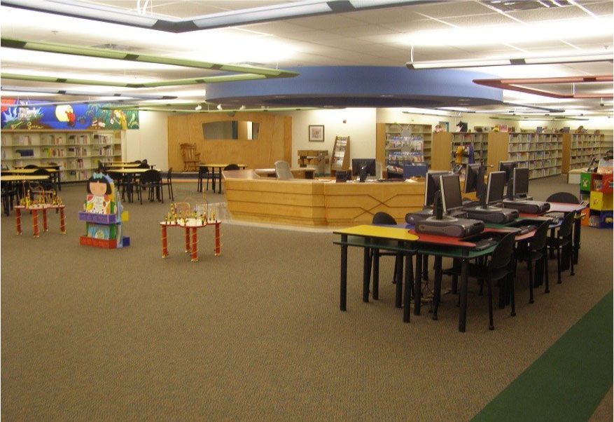 A children 's library with tables and chairs and computers