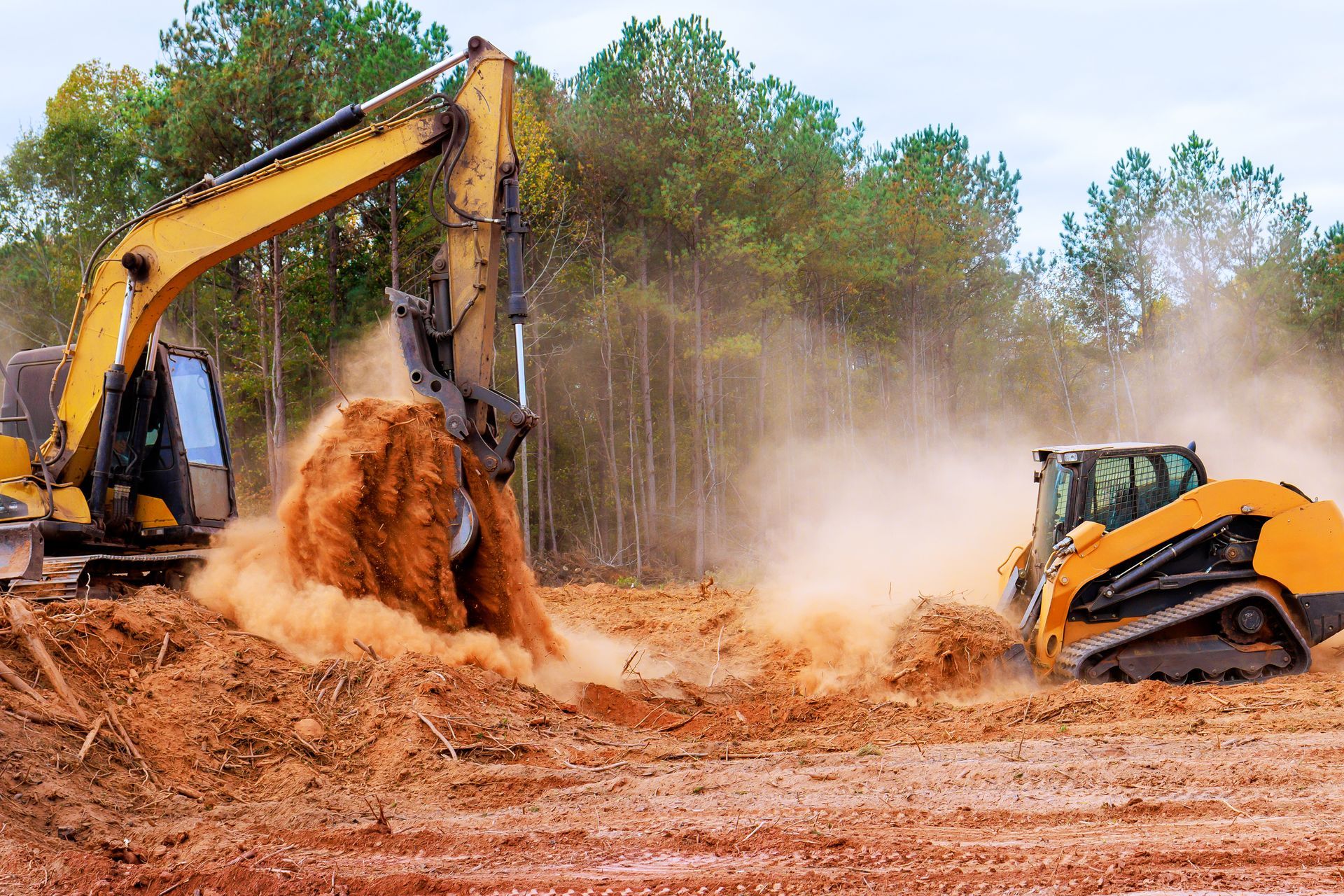 Yellow excavator and bulldozer stirring dusty soil at a construction site