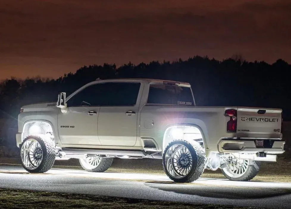 A white truck is parked on the side of the road at night.