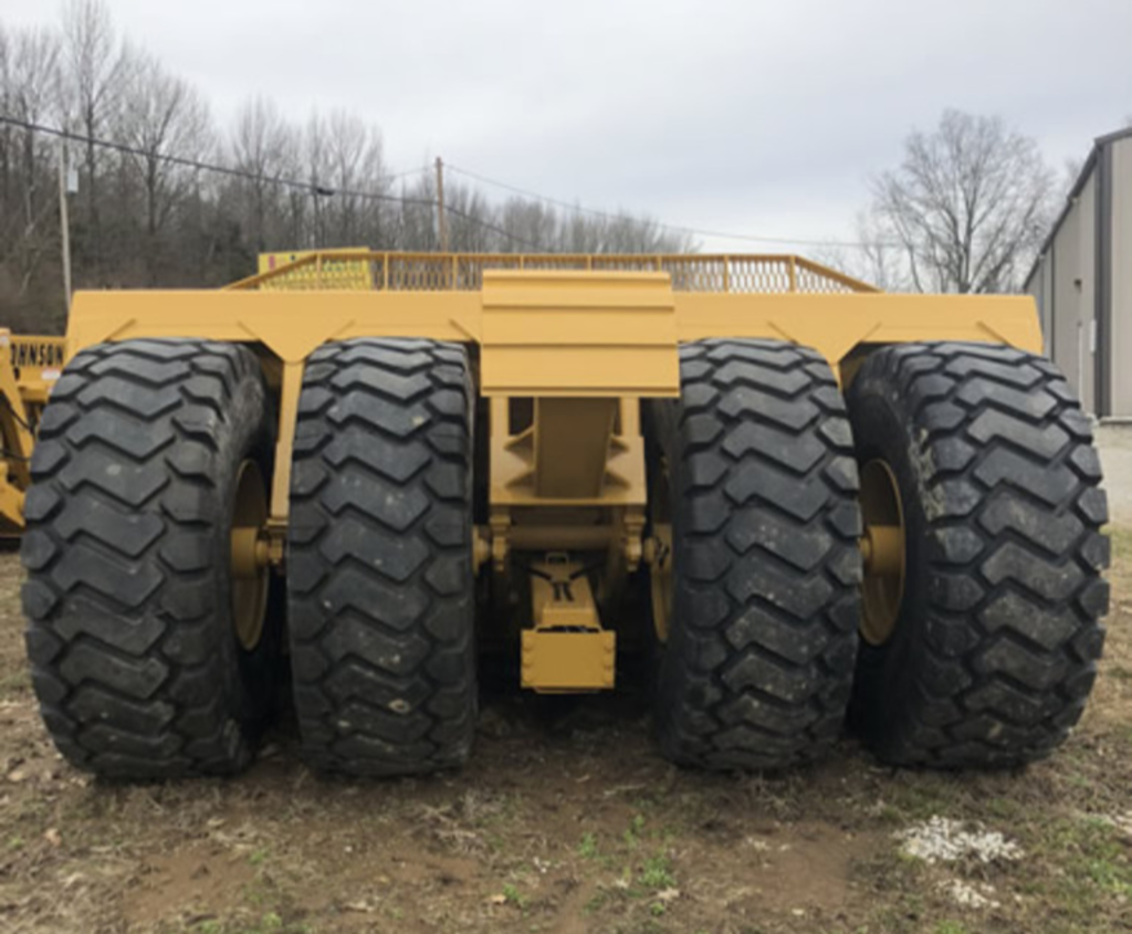 A yellow trailer with a lot of tires on it is parked in a field.