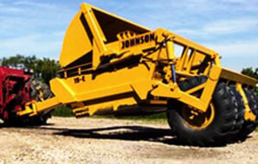 A yellow johnson tractor is parked on a dirt road.