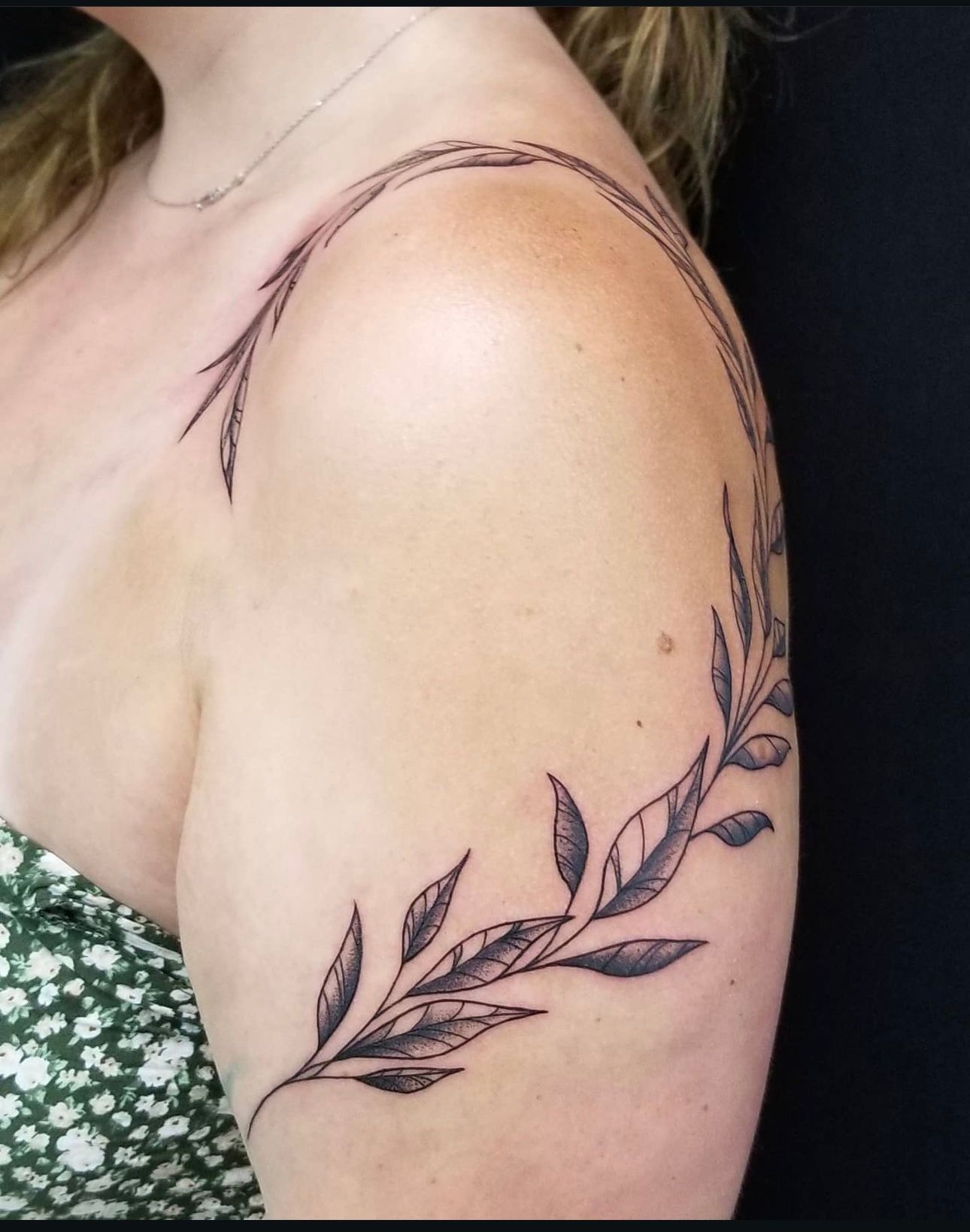 A woman has a tattoo of leaves on her shoulder