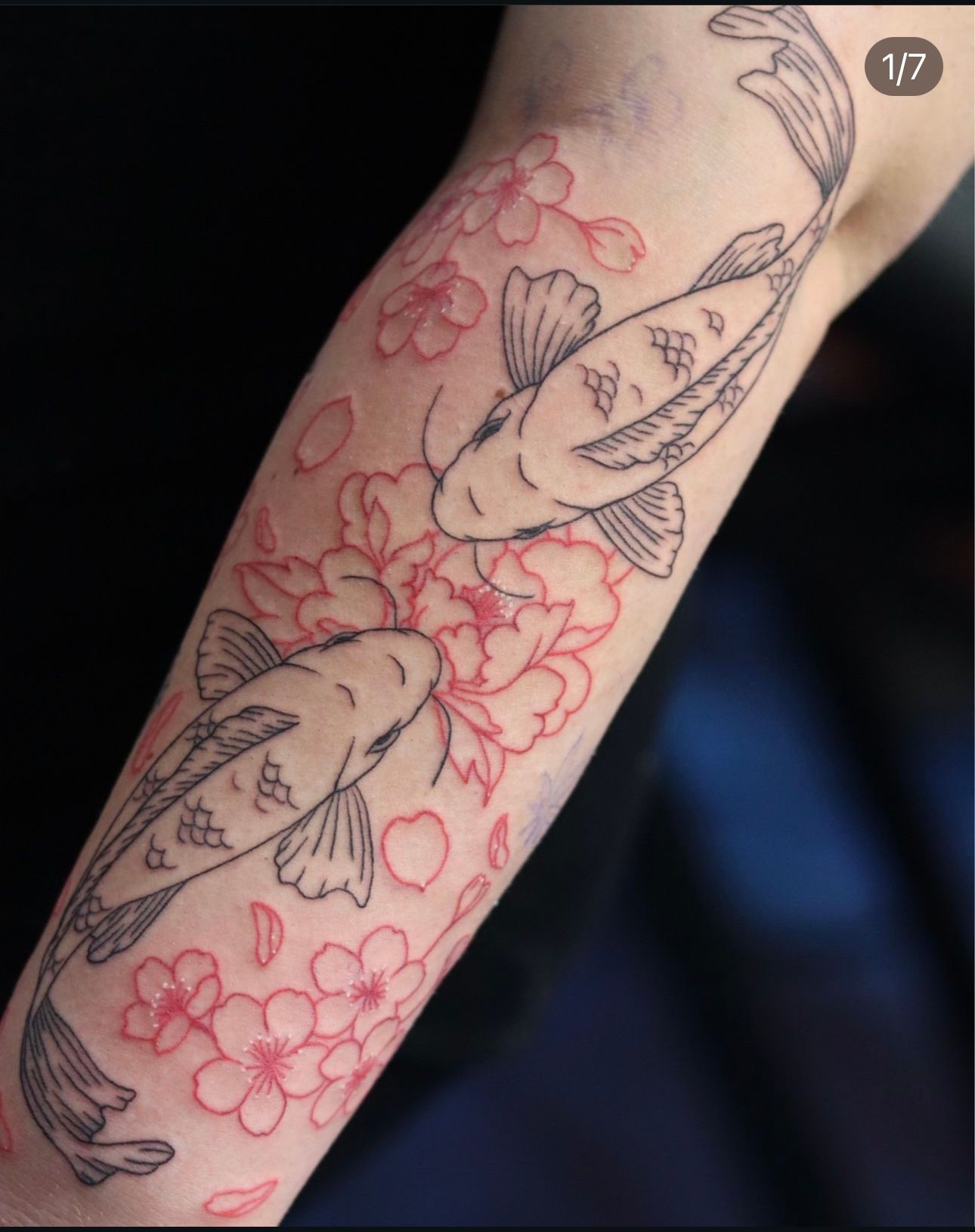 A tattoo of two fish and flowers on a person 's arm