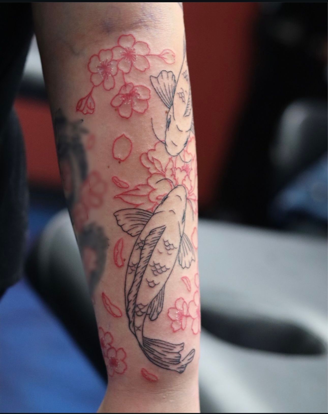 A tattoo of two fish and flowers on a person 's arm