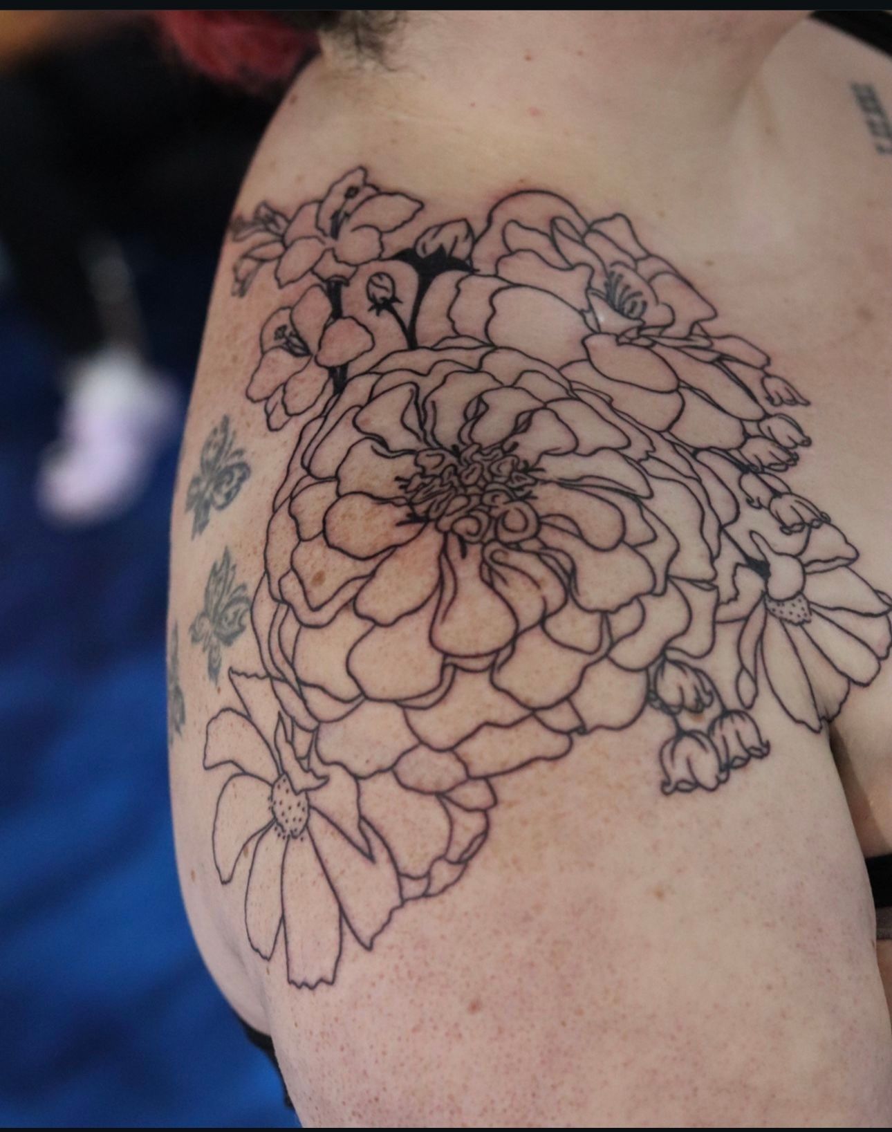 A woman has a tattoo of flowers on her shoulder
