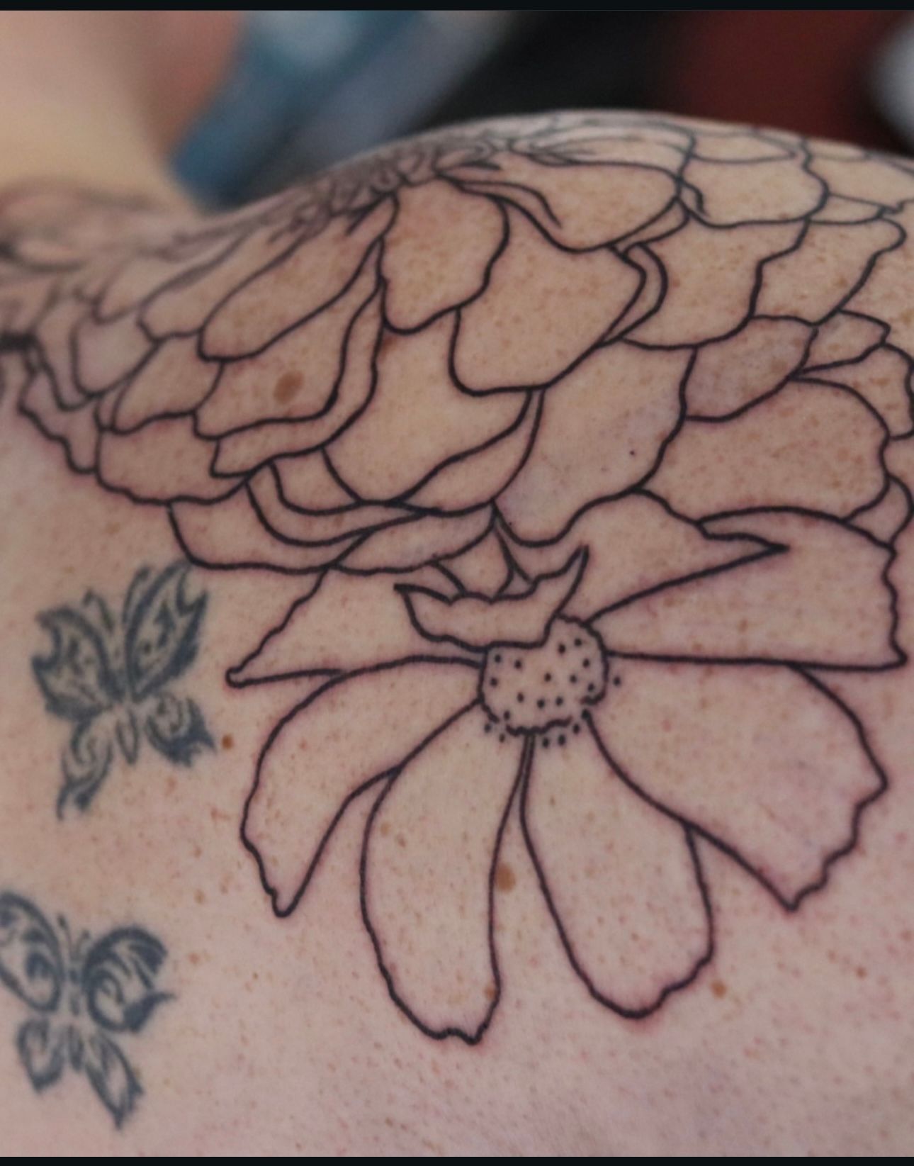 A woman has a tattoo of a flower on her shoulder