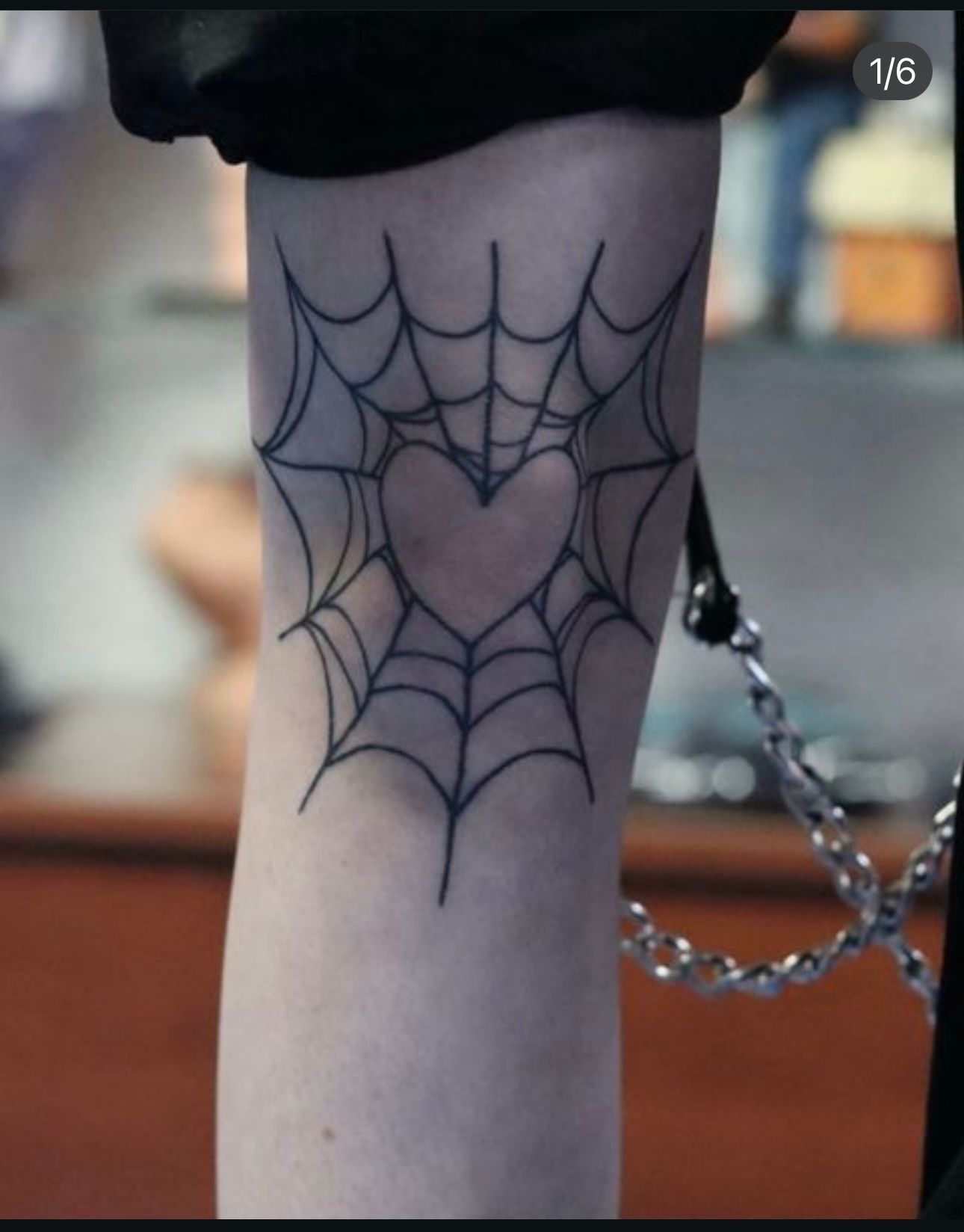 A tattoo of a spider web with a heart in the middle