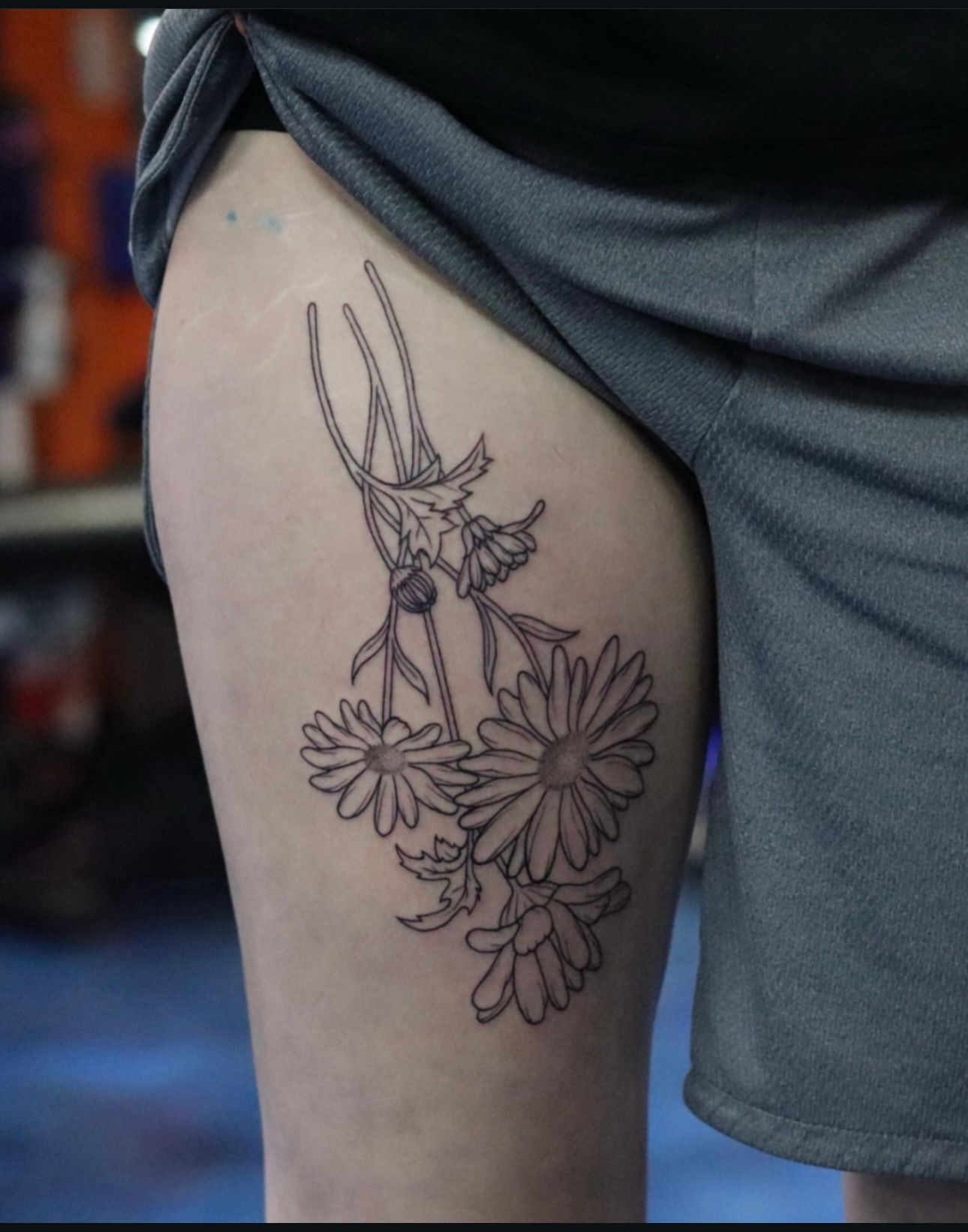 A woman has a tattoo of daisies on her thigh