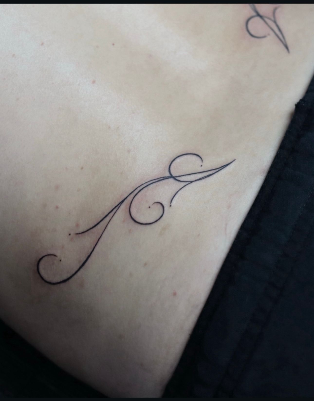 A person has a tattoo of the letter a on their back