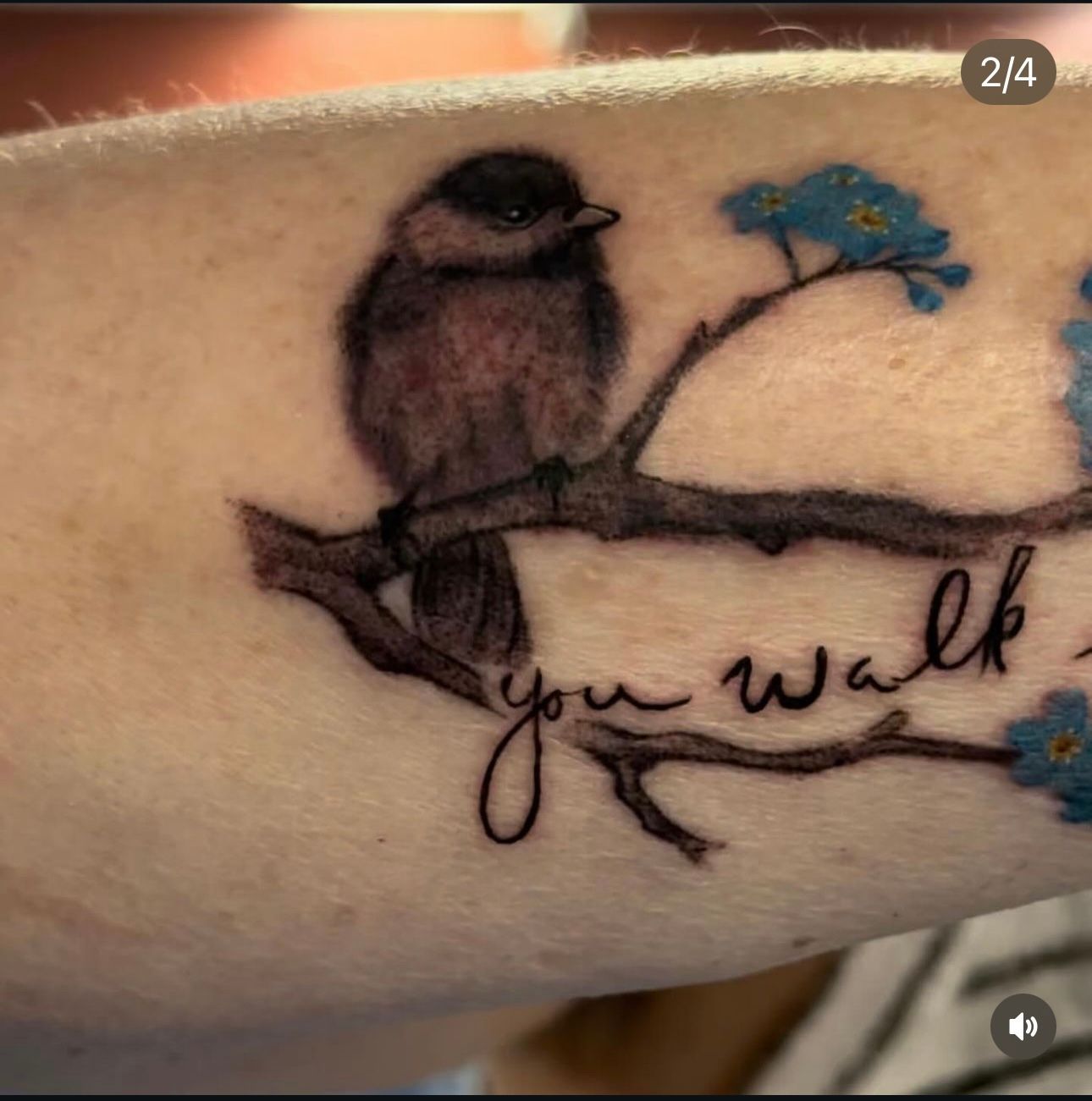 A tattoo of a bird on a branch with the words 