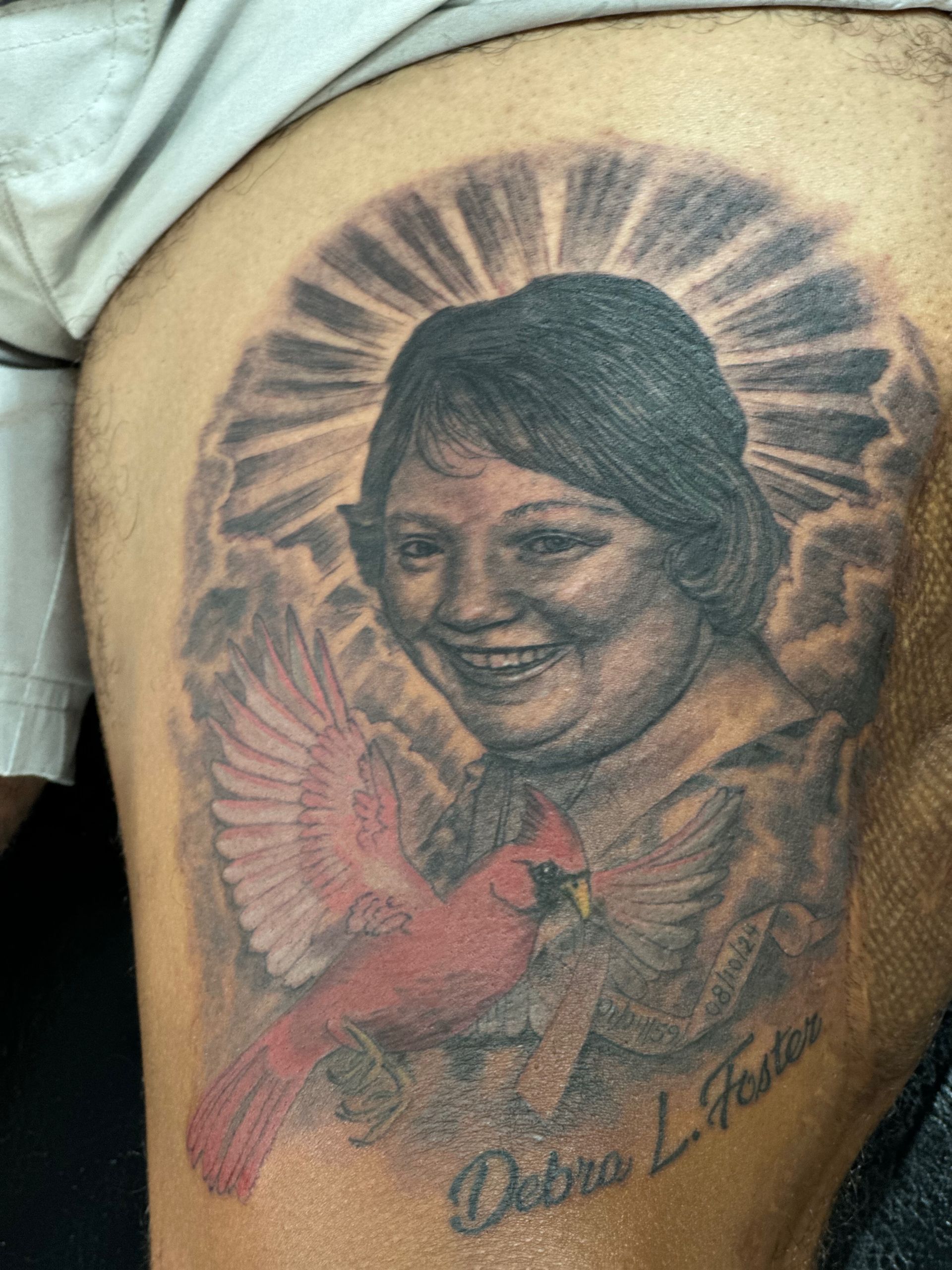 A man has a tattoo of a woman and a bird on his thigh.
