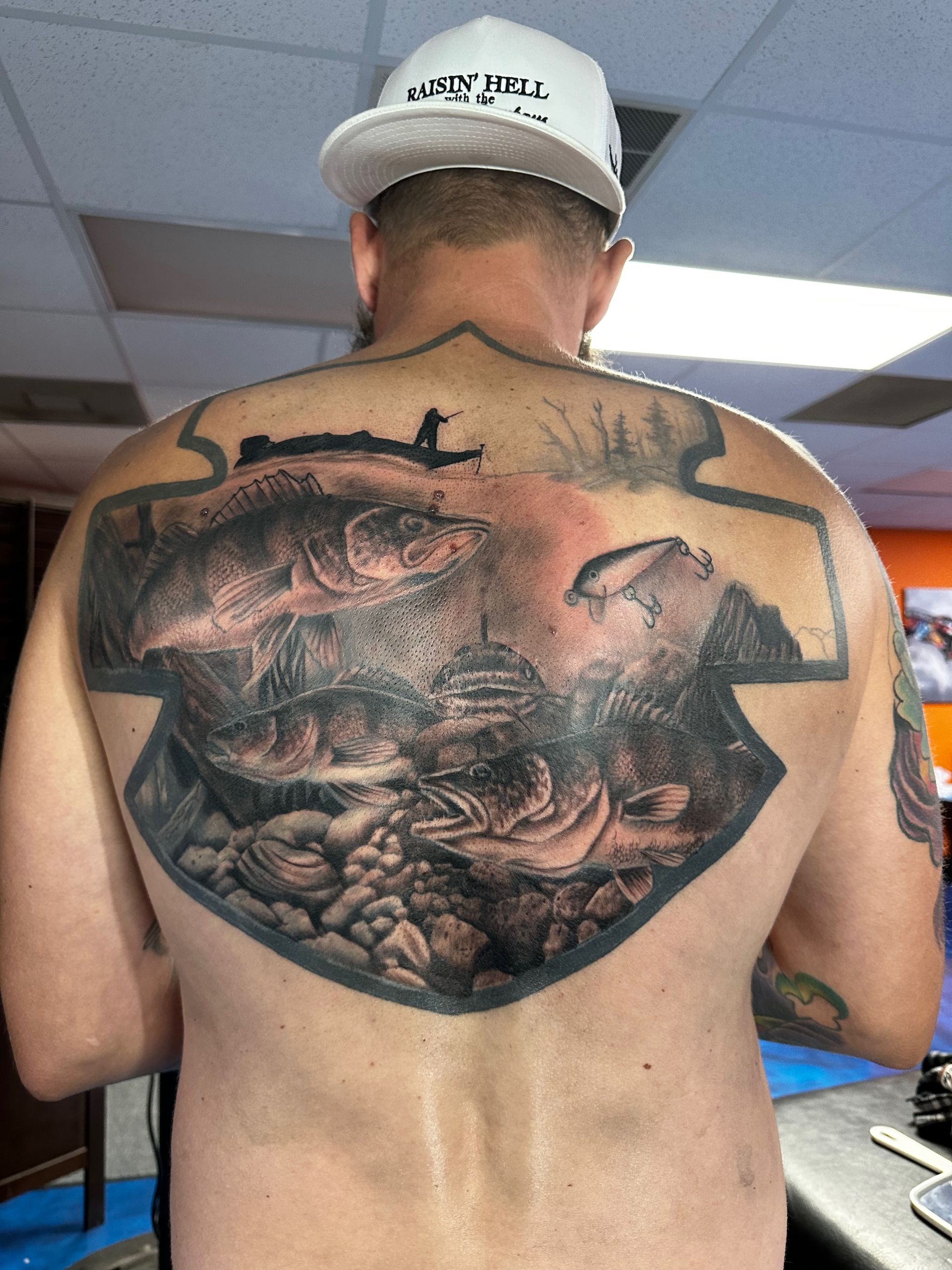 A man with a tattoo on his back is wearing a hat.
